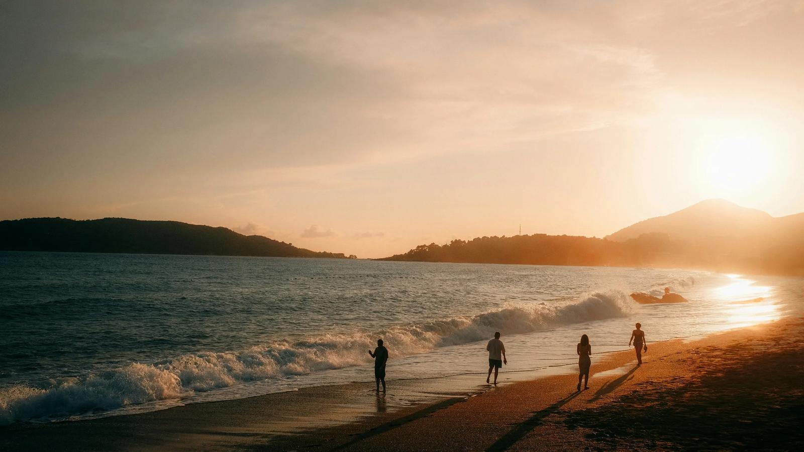 People walking on a beach at sunset