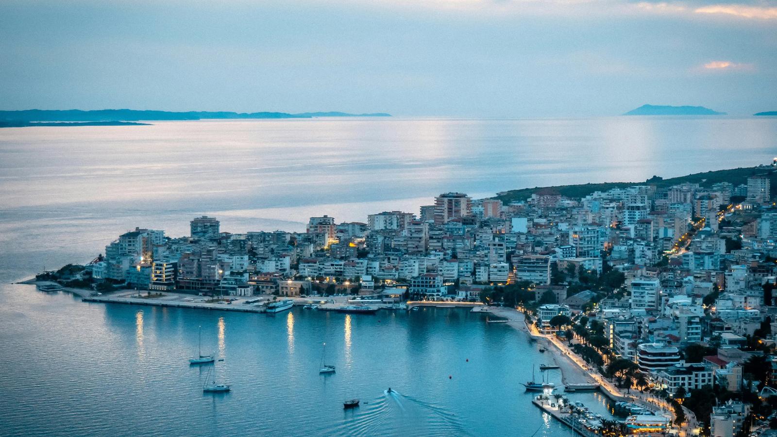City lights illuminate a scenic waterfront at dusk.