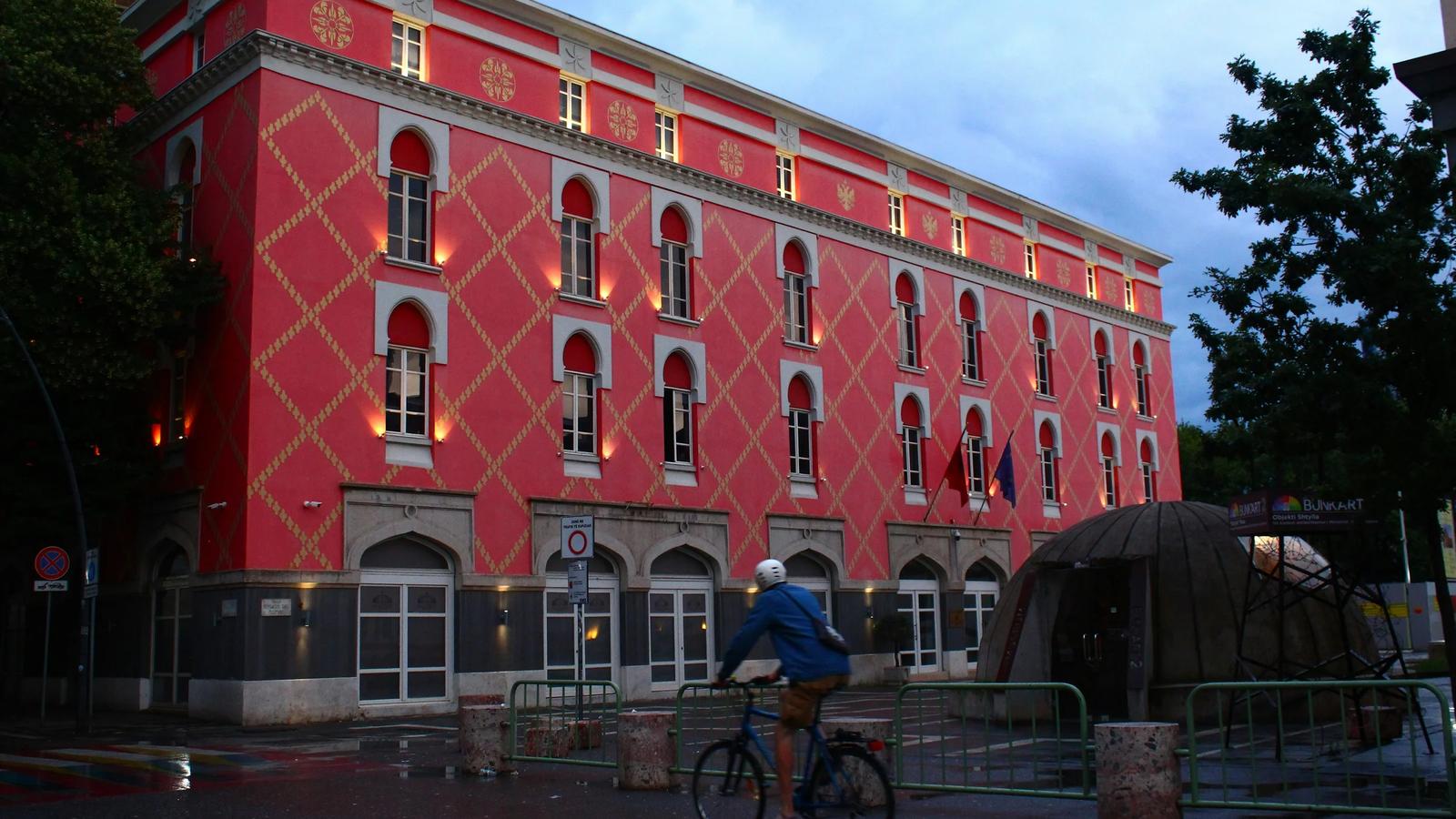 a man riding a bike past a red building
