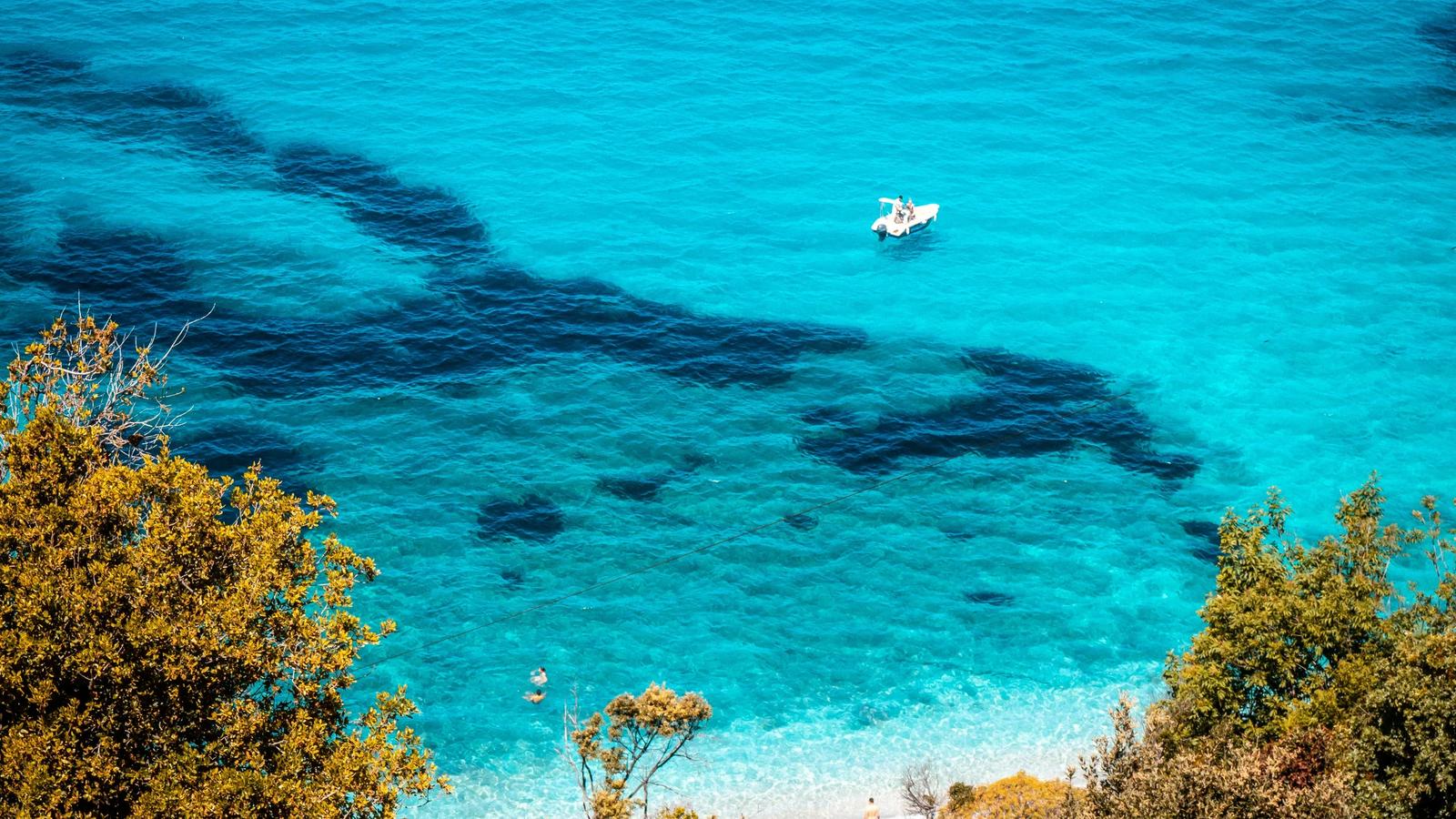 Beautiful turquoise water with a boat and greenery.