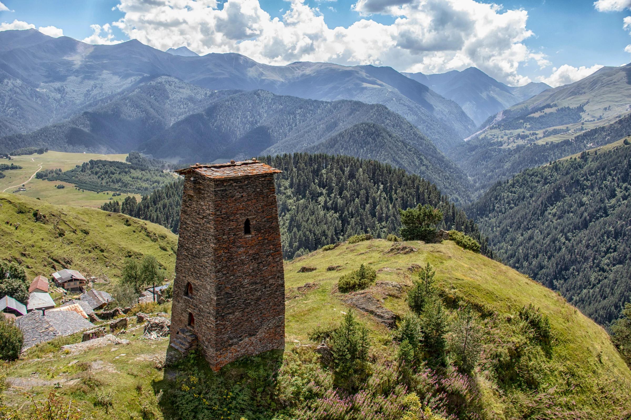A tall tower sitting on top of a lush green hillside