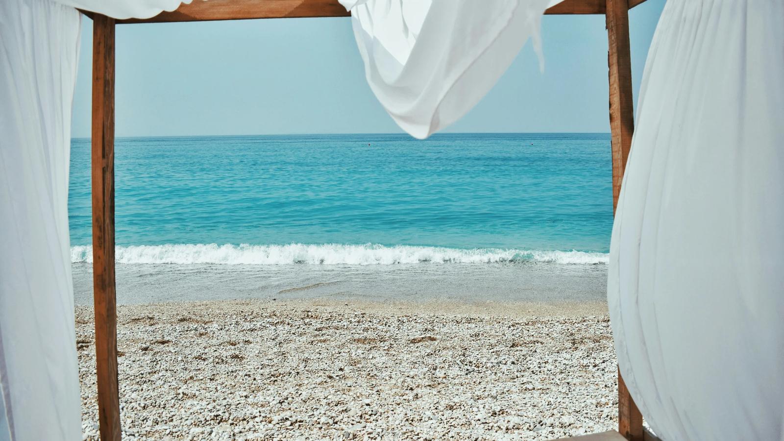 a bed sitting on top of a sandy beach next to the ocean