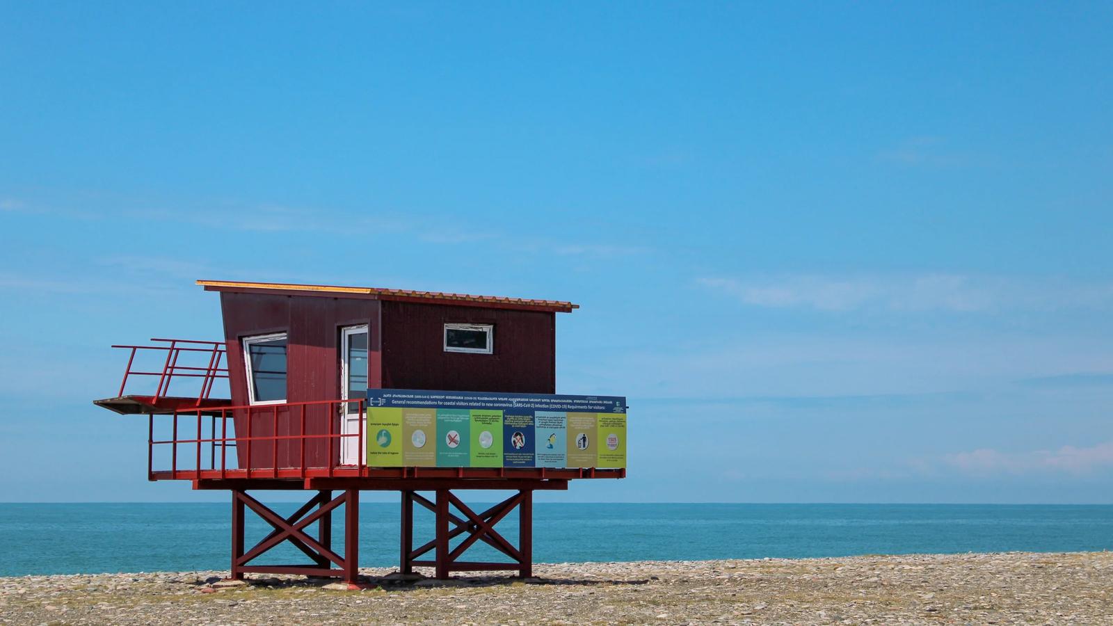 red and white wooden lifeguard house on beach shore during daytime