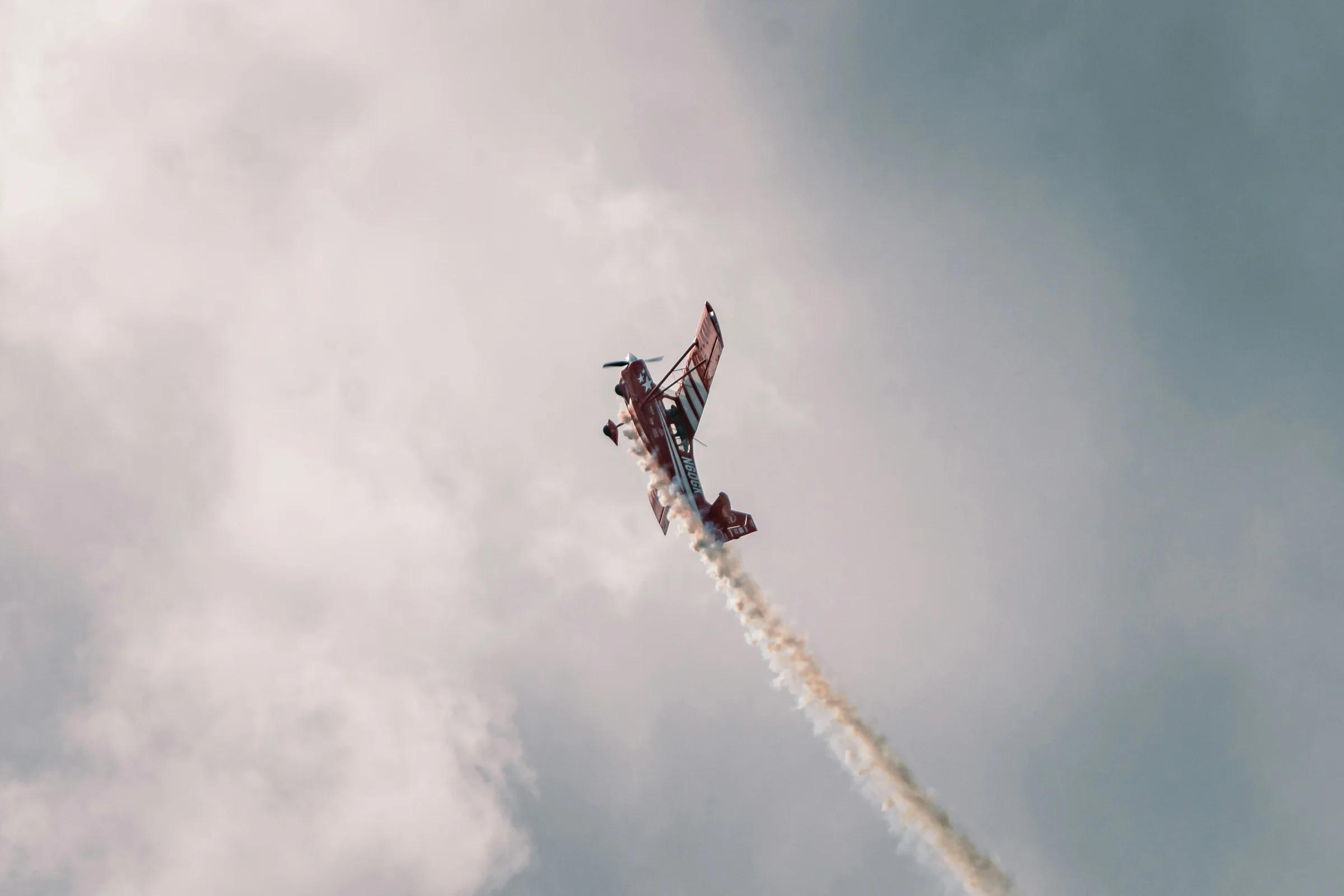 a red and white plane flying through a cloudy sky