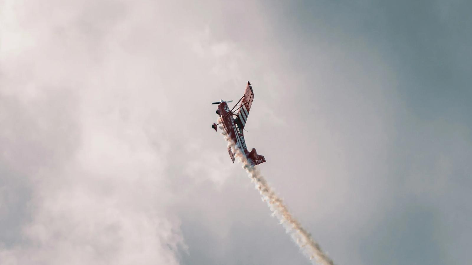a red and white plane flying through a cloudy sky