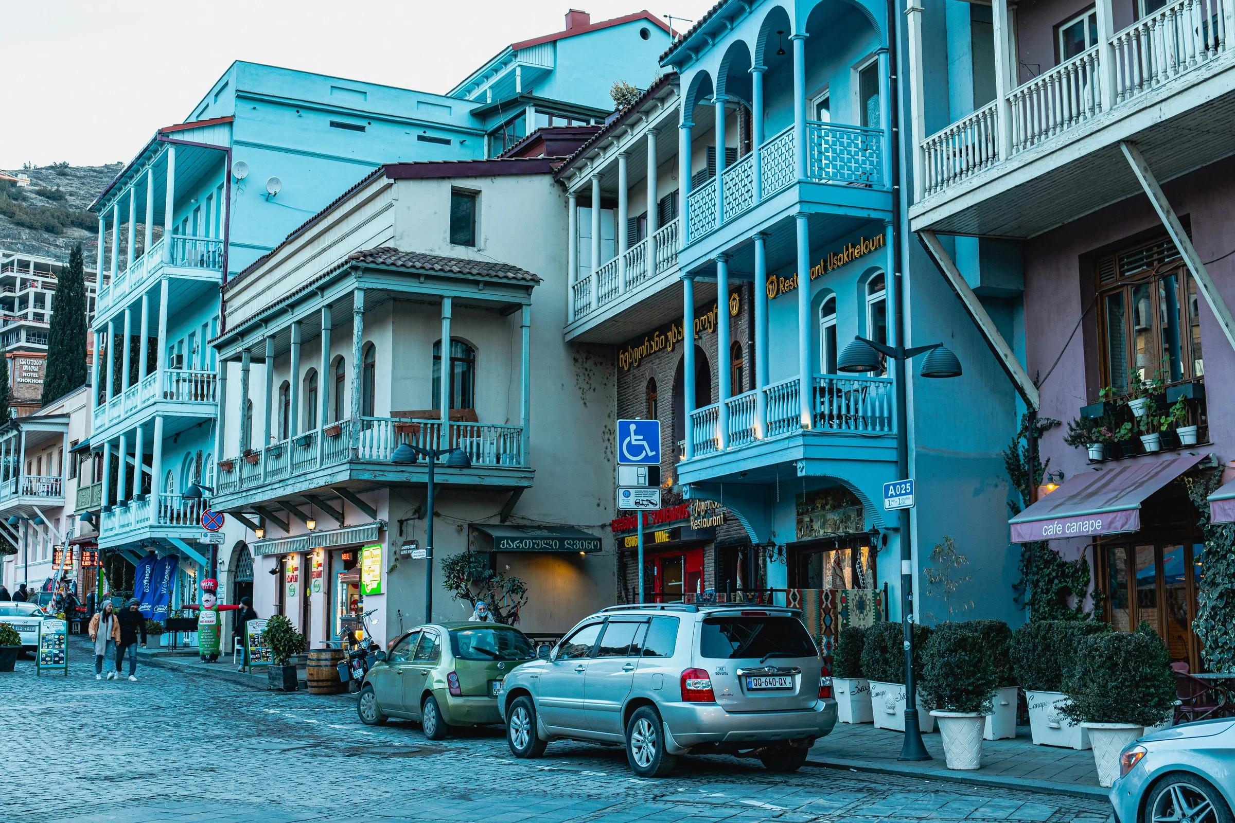 a row of buildings with cars parked on the side of the street