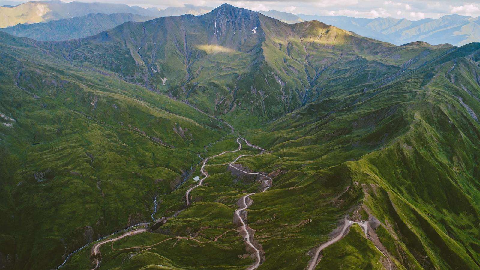 roads on hill under cloudy sky at daytime