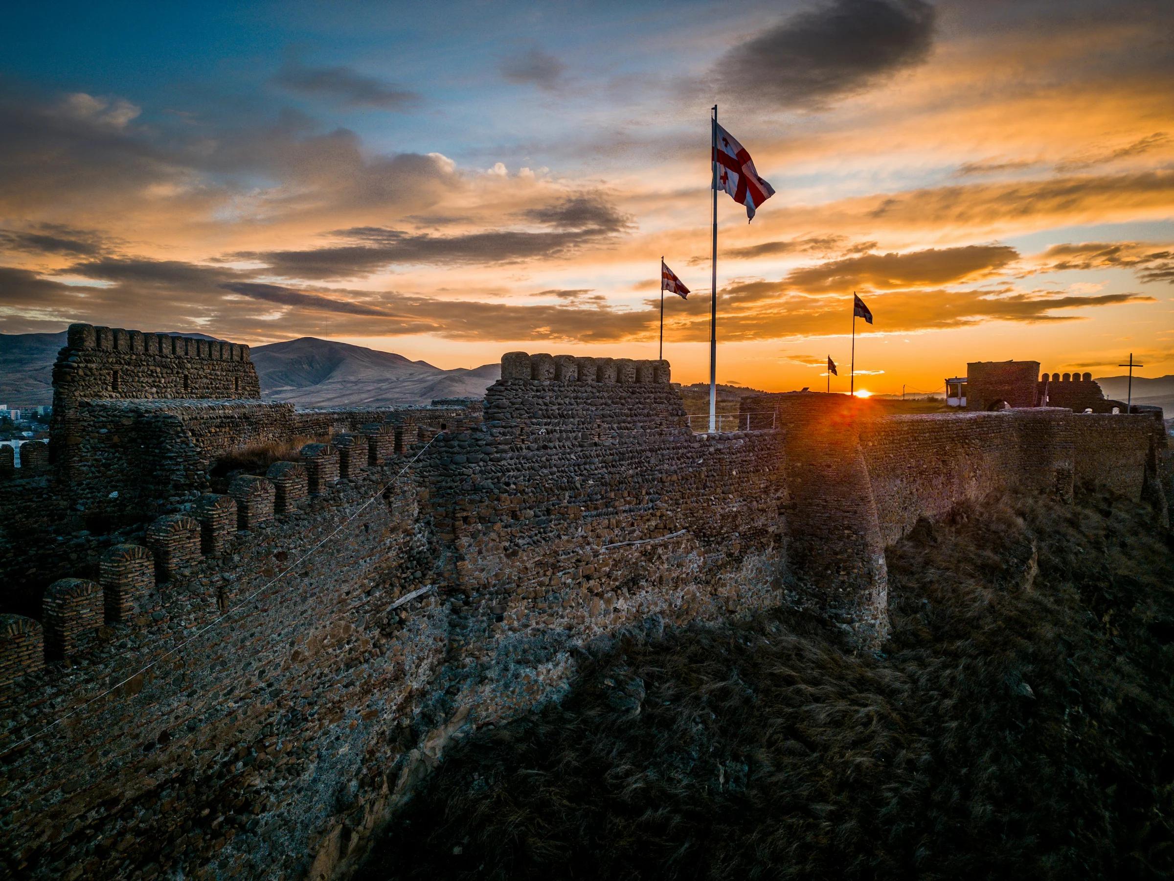 the sun is setting over a castle wall