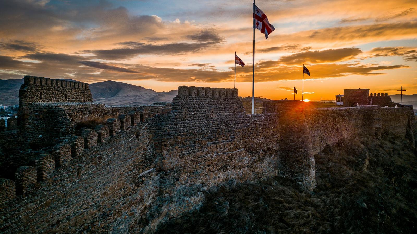 the sun is setting over a castle wall