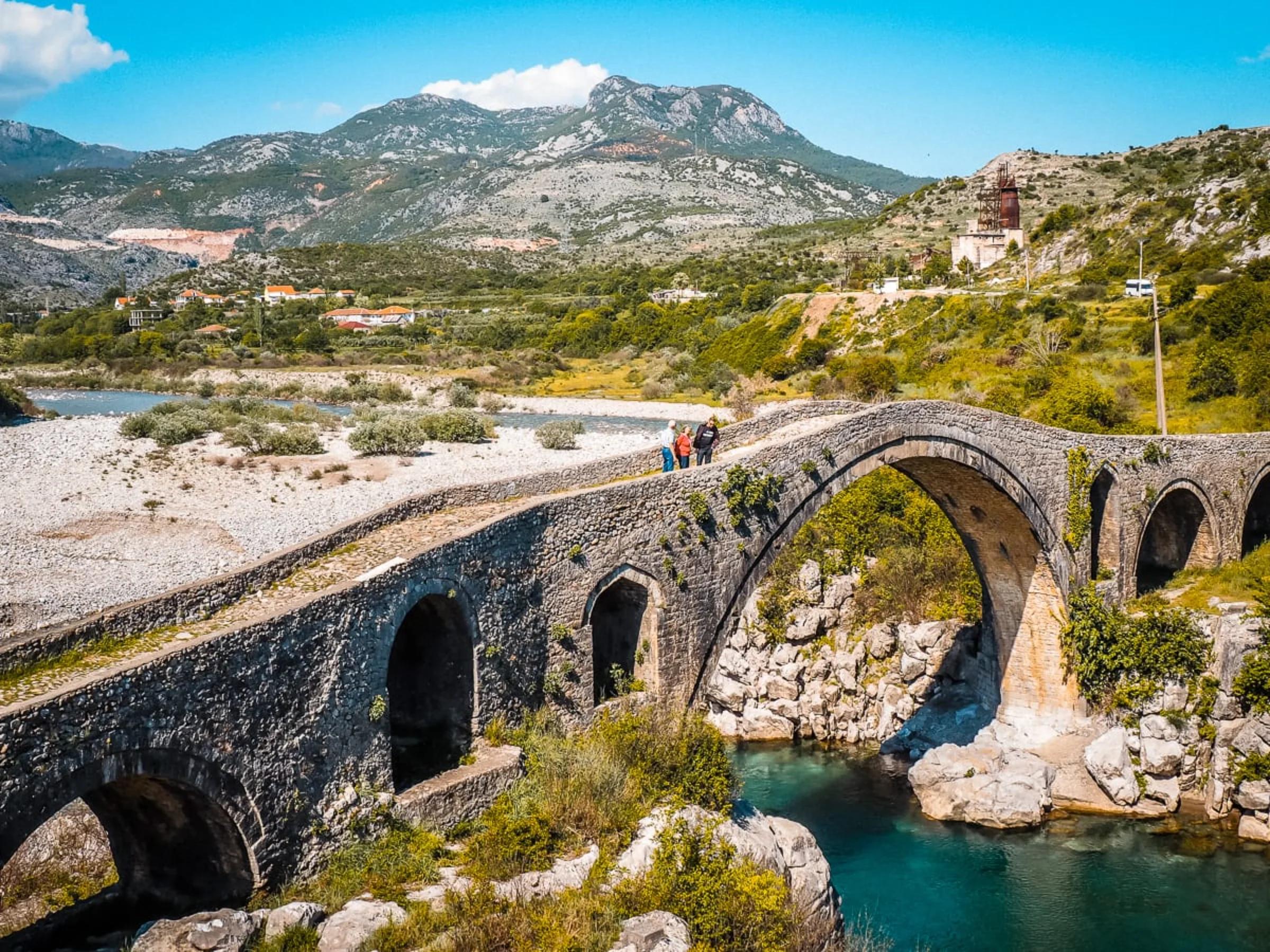 An ancient stone bridge over a turquoise river.