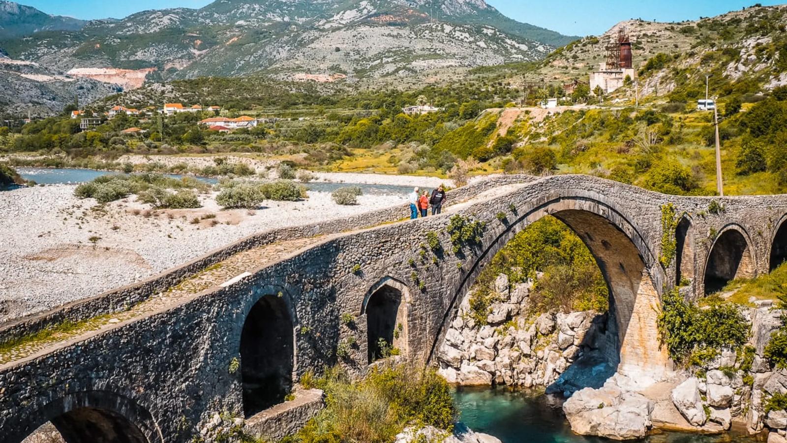 An ancient stone bridge over a turquoise river.