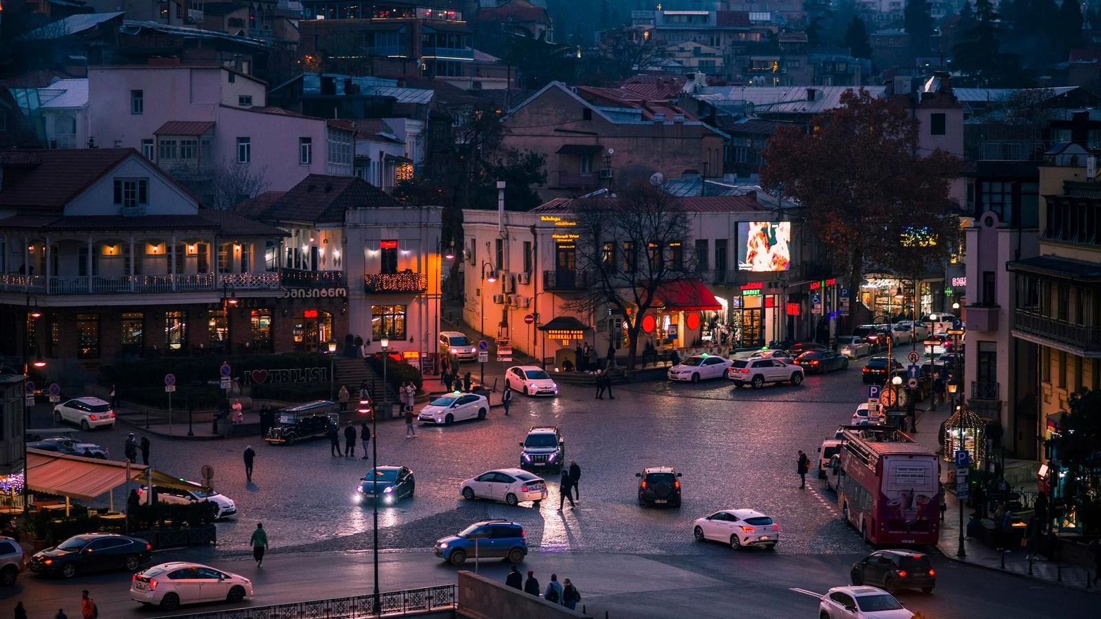 a city street filled with lots of traffic next to tall buildings