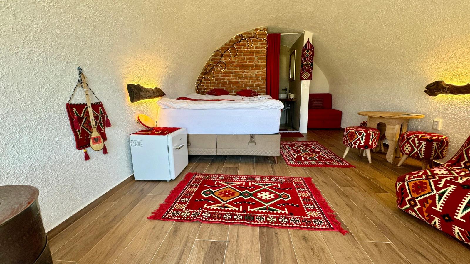 A room with a bed, couch, and rugs on the floor