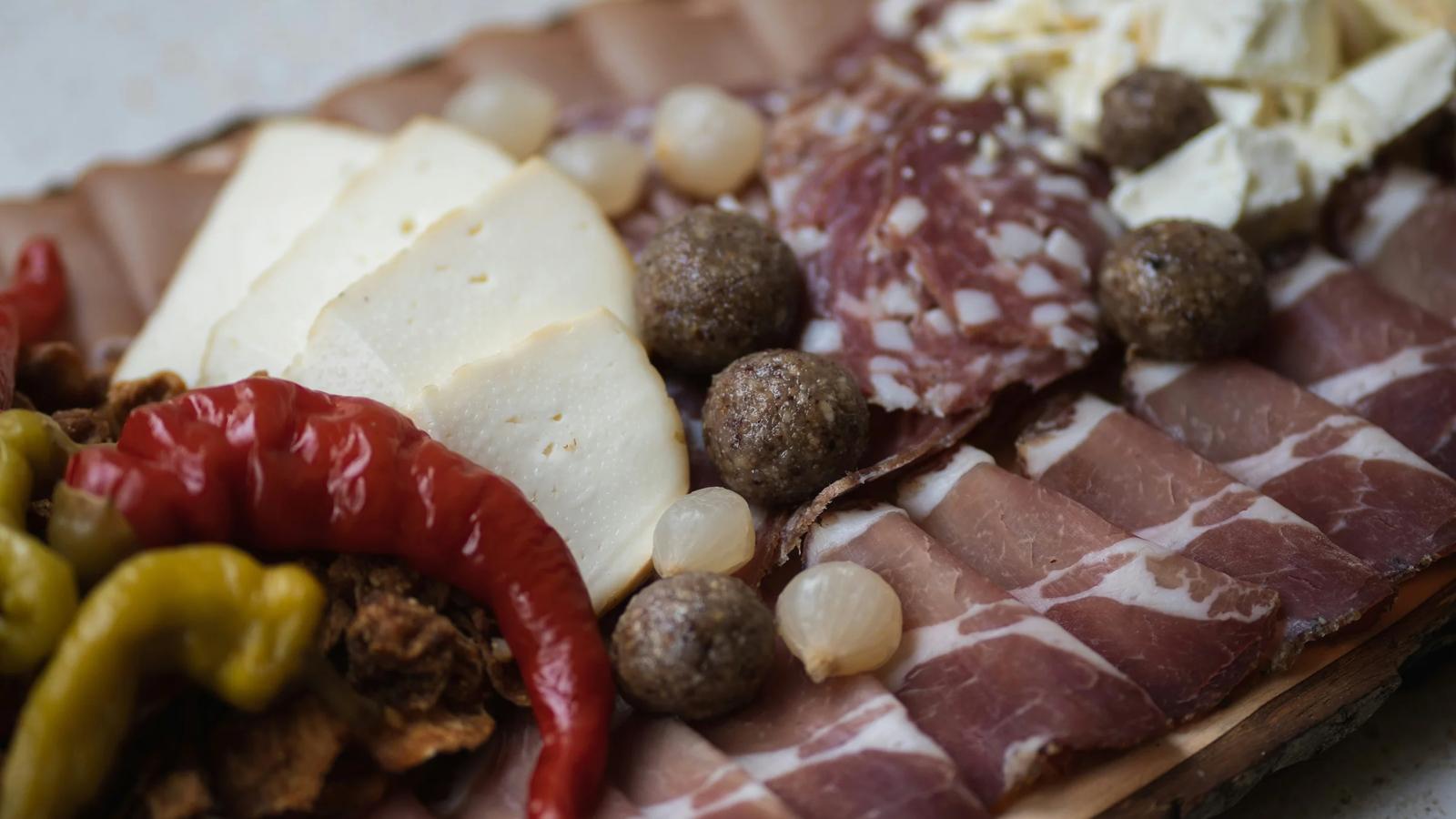 a platter of meats and cheeses on a cutting board