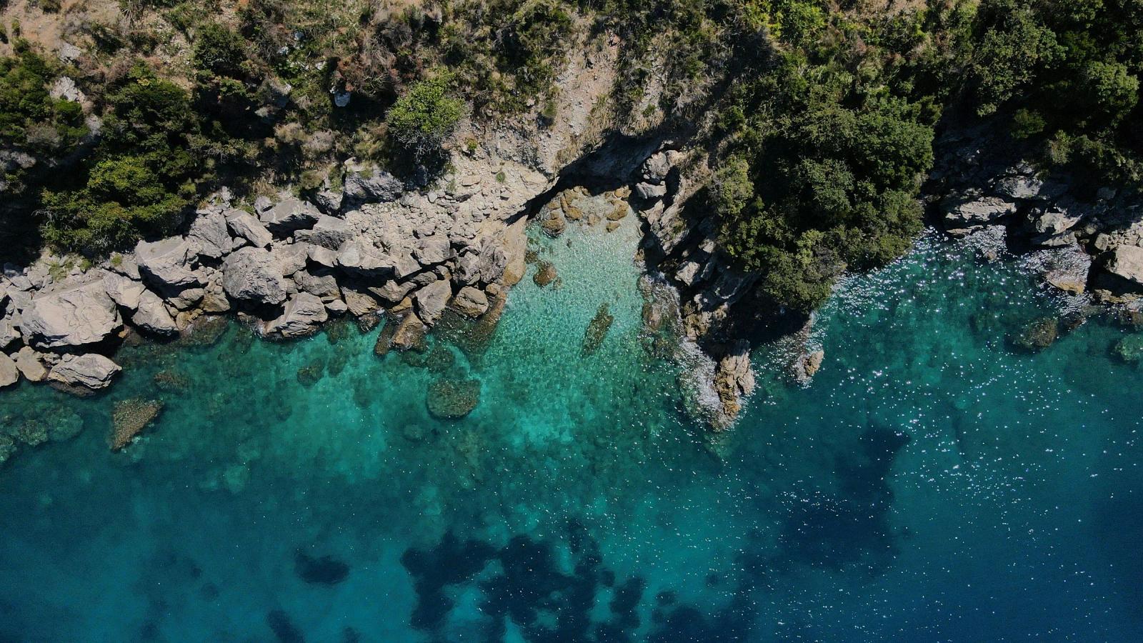aerial view of green and brown rocky mountain beside body of water during daytime