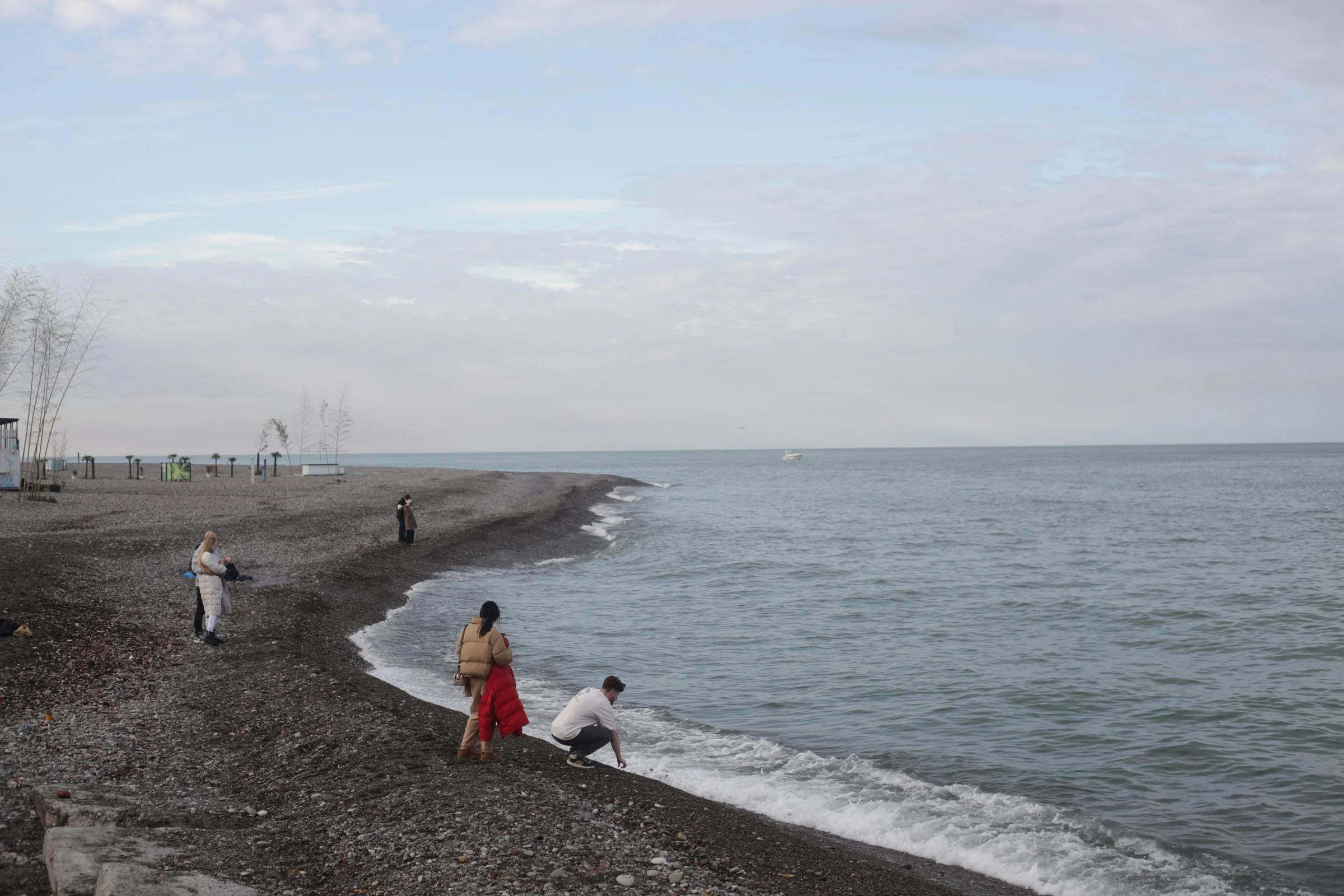 a group of people standing on top of a beach next to the ocean