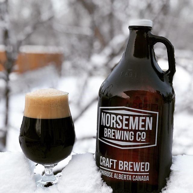 A growler and glass of brew in the snow