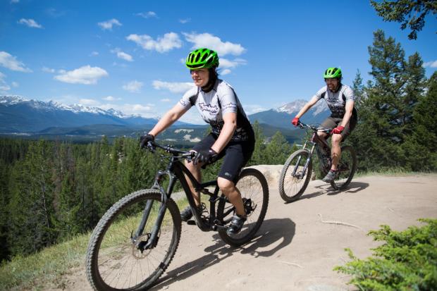 People mountain biking on trail through the mountains in Jasper.