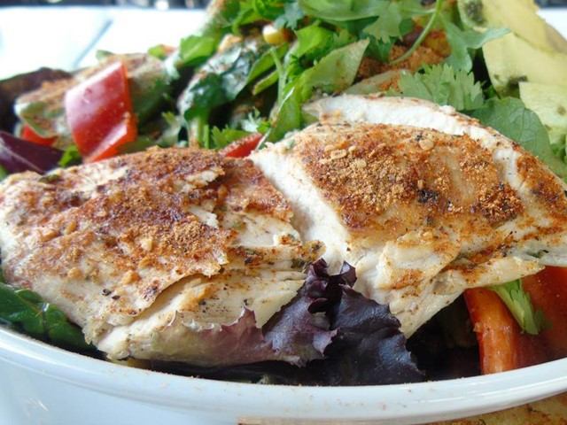 Cooked flatbread with spiced surface, greens, tomatoes, and salad greens on a plate.