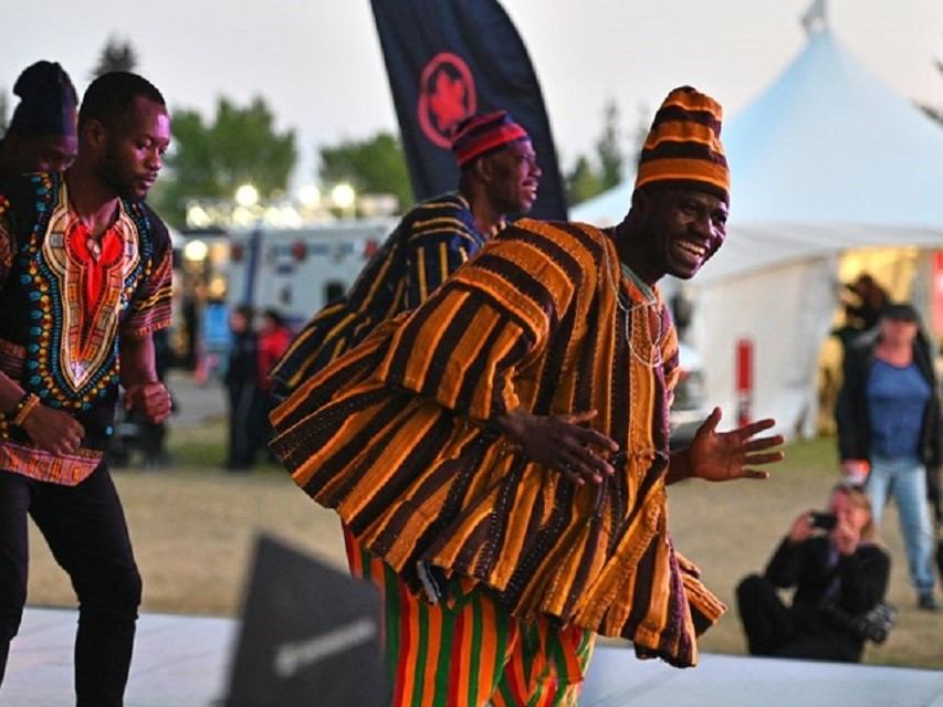 Dancers in striped traditional outfits perform at GlobalFest with tents in the background.