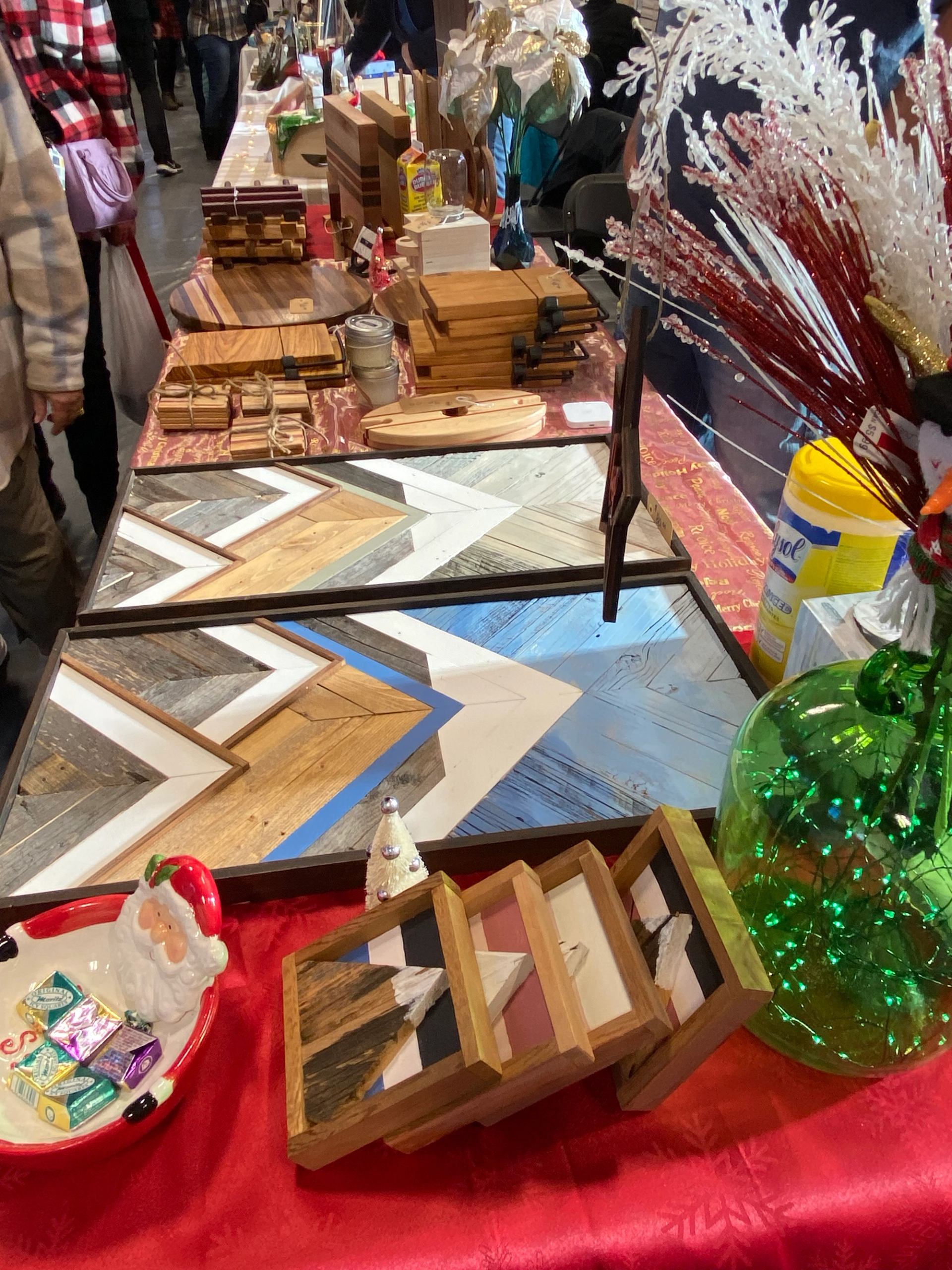 Table display of handcrafted wooden art pieces and geometric designs at a holiday market.