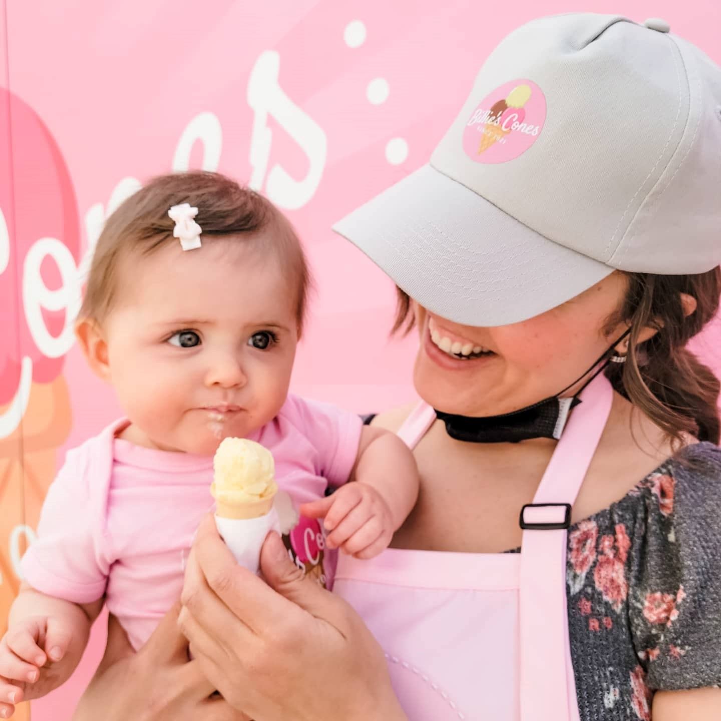 A child held in a womans arms eating a ice cream cone