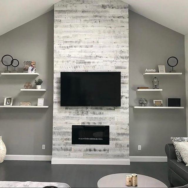 Living room wall with whitewashed wood panel, TV, fireplace and floating shelves.