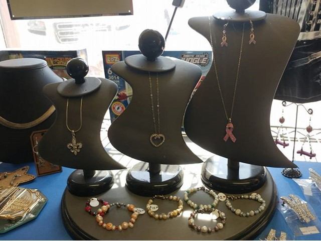 Jewellery displays on mannequin torsos with necklaces on a table, inside a retail shop.