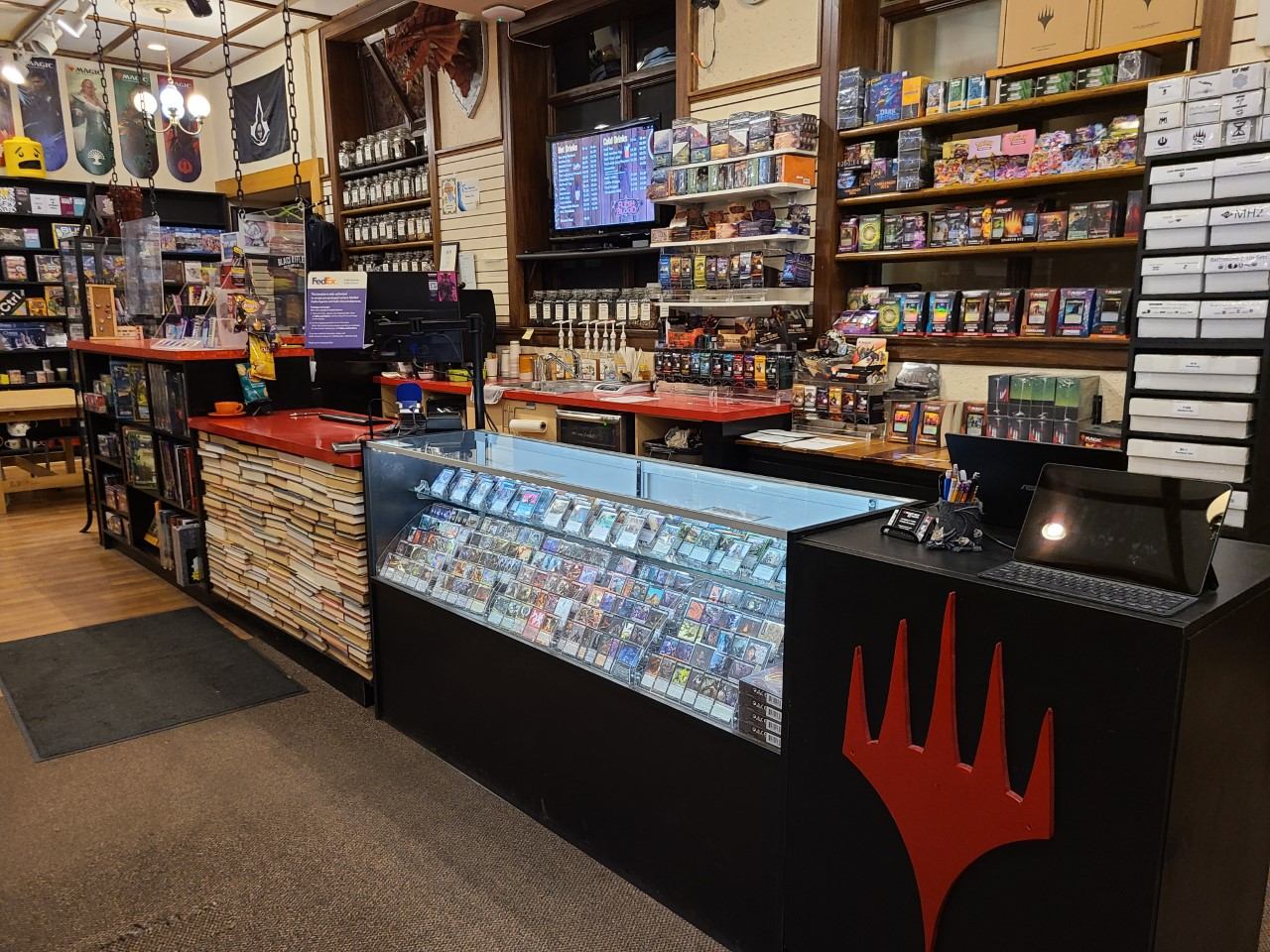 Coffee shop counter with display case, shelves of packaged goods, and beverage dispensers.