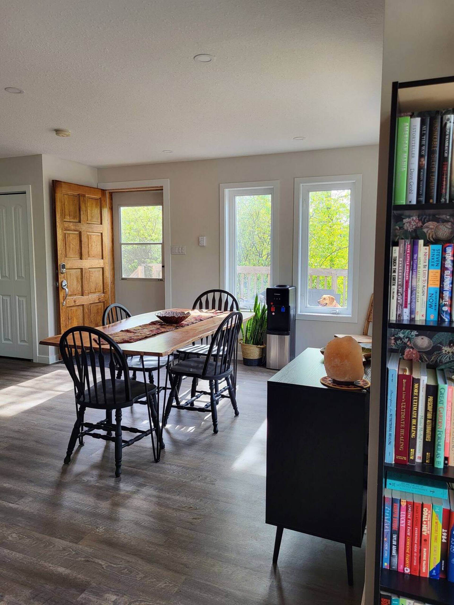 A dining area with a wooden table, large windows, and natural light filling the room.