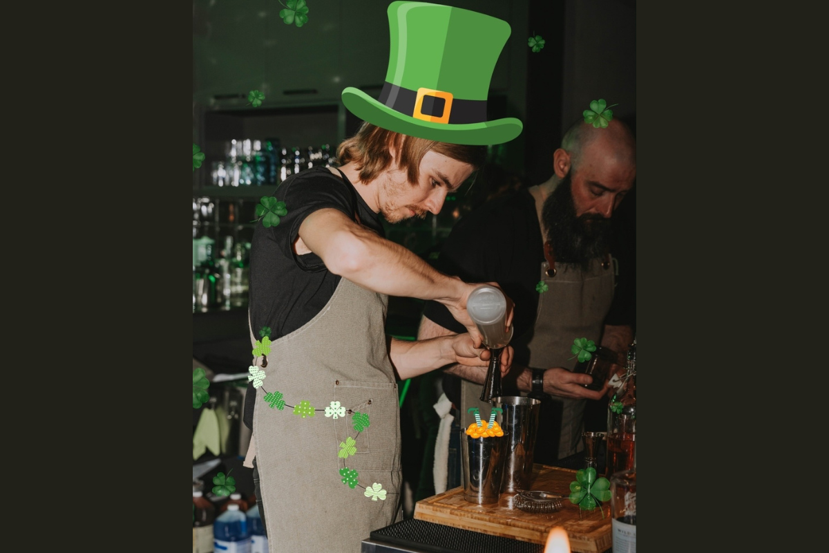 Bartender mixing a drink at a St. Patrick’s Day–themed trivia night, with green decorations and bar tools visible.