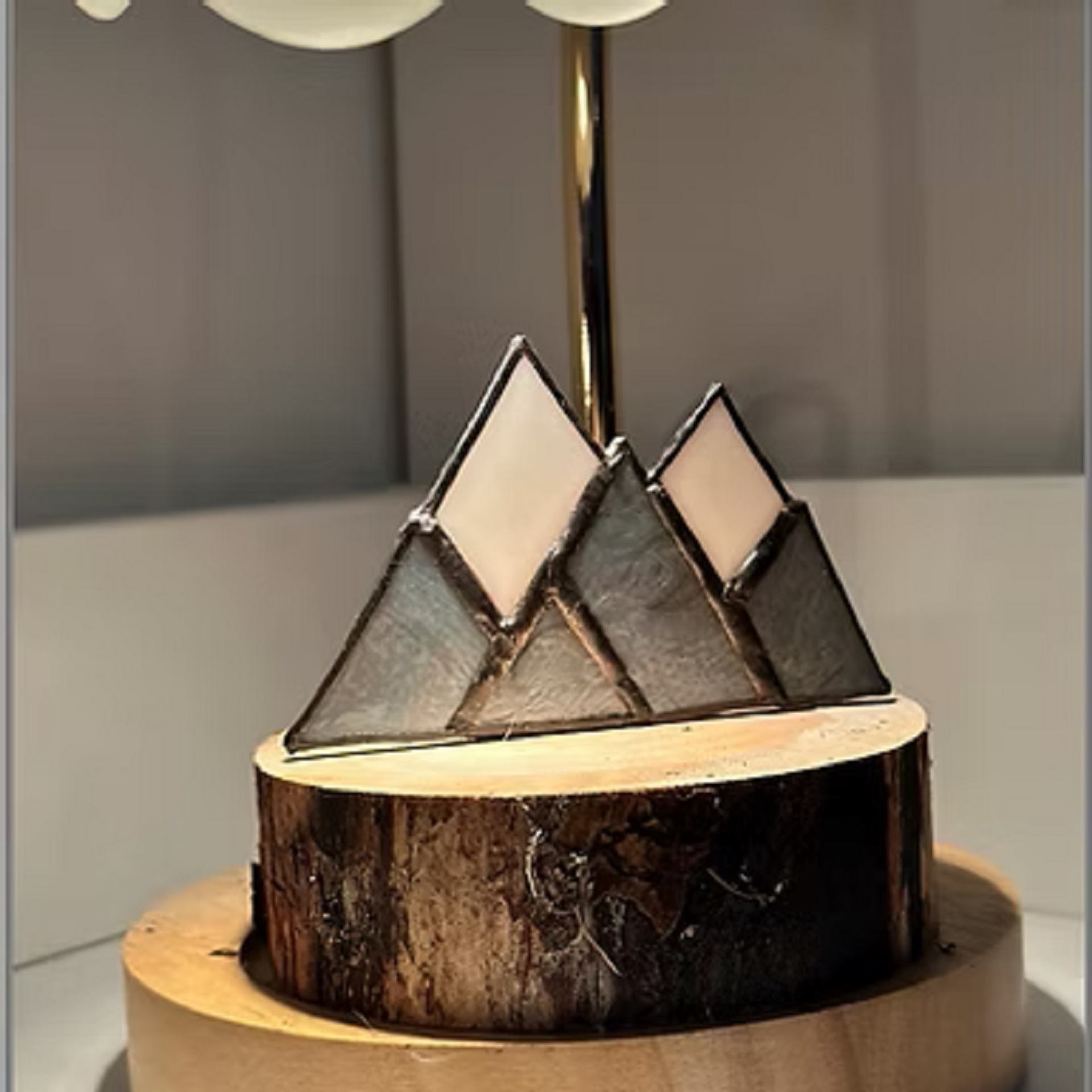 Stained glass with white peaks and gray bases on a wooden log base.