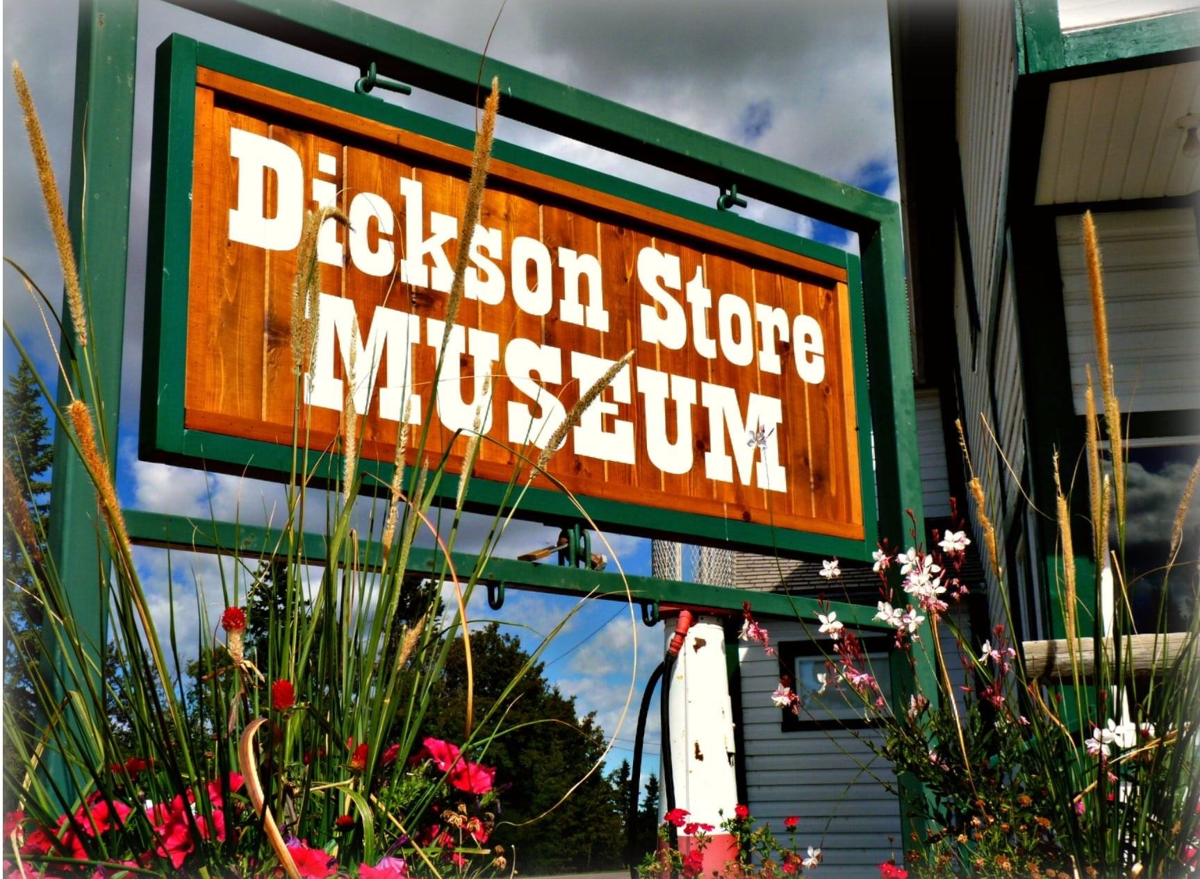 Wooden “Dickson Store Museum” sign with green frame and flowers in foreground.