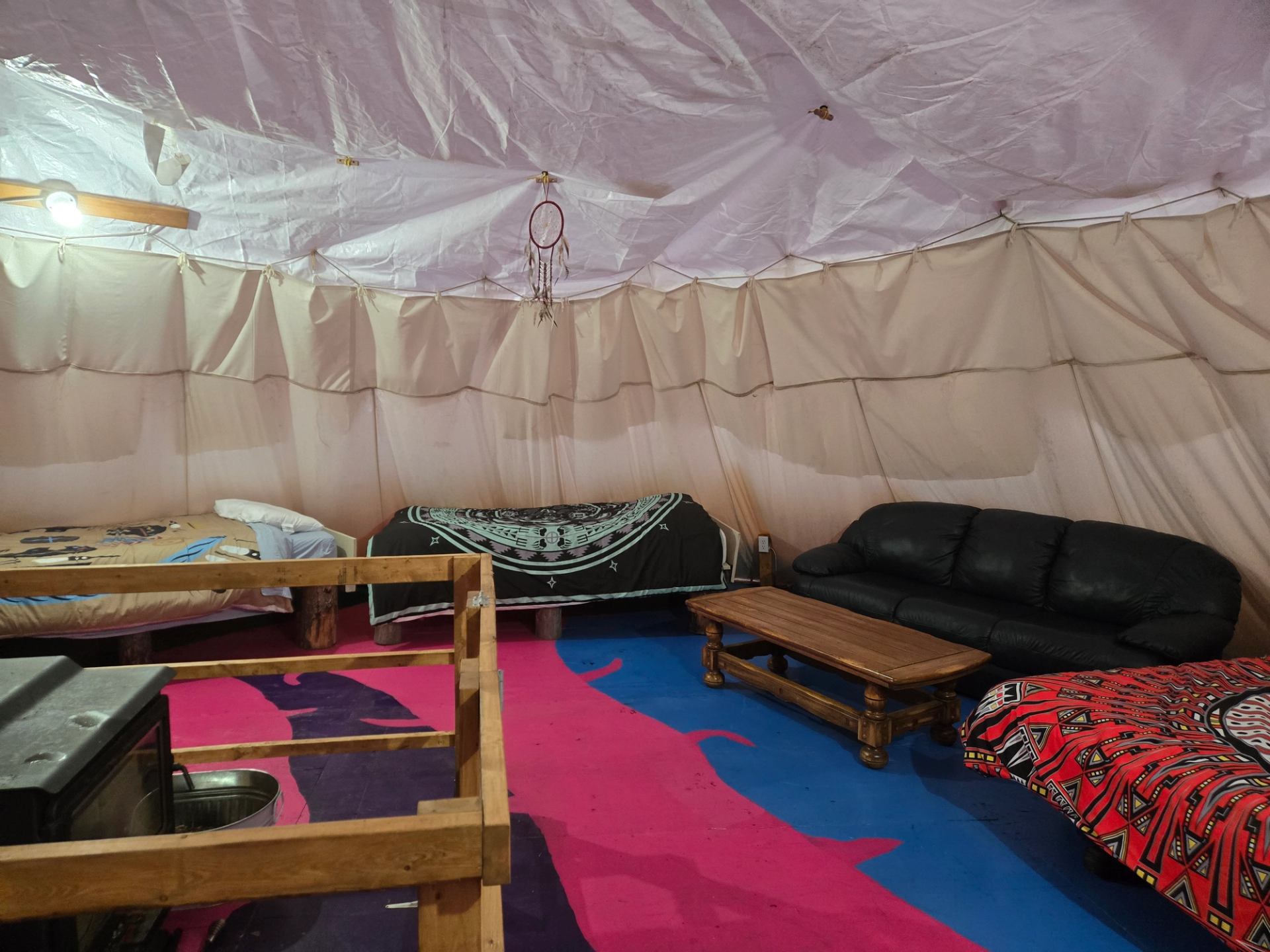 Inside 30ft teepee, domed inside, 2 twin beds, couch, queen bed, fireplace, floor painted in aurora