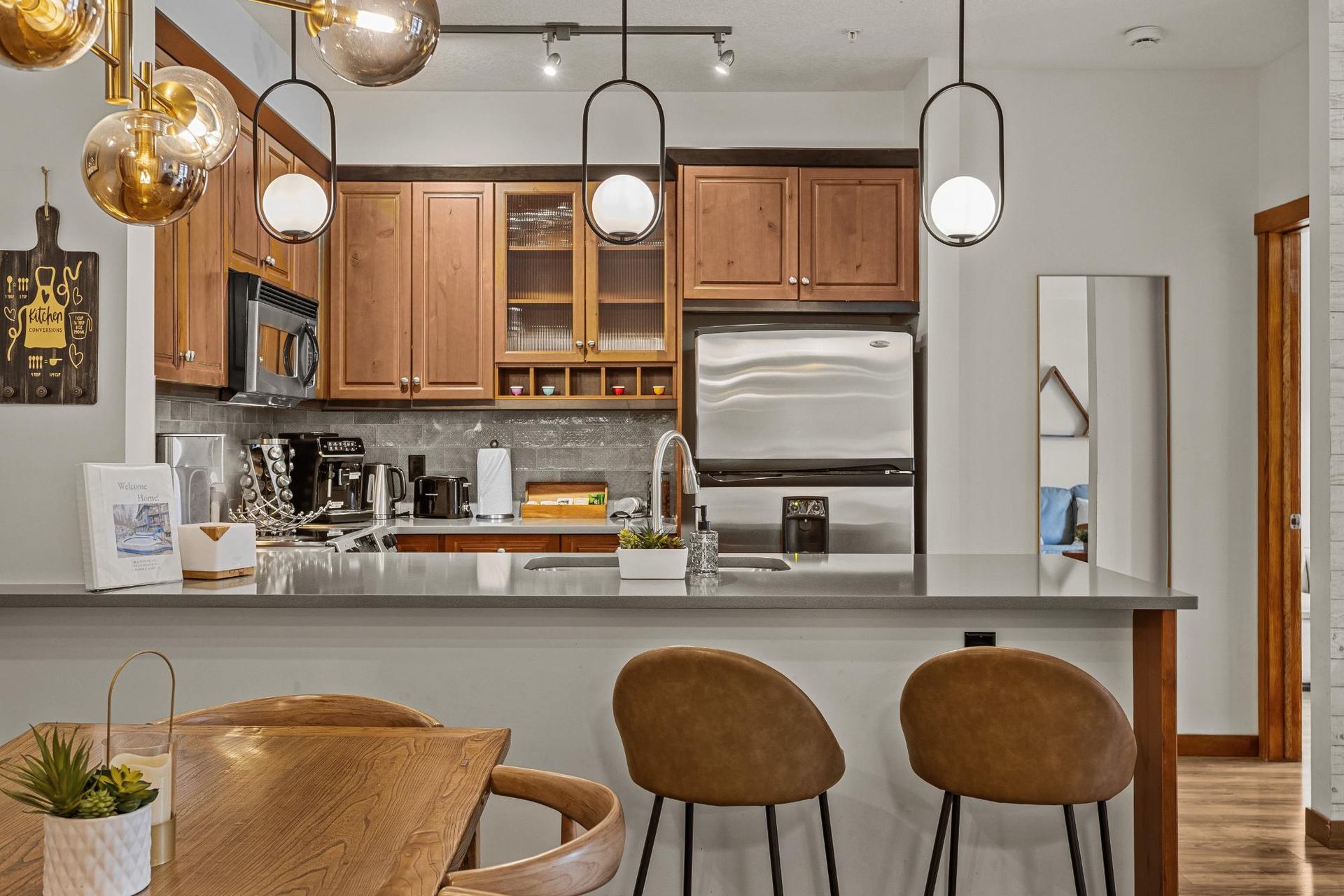 Modern kitchen with wood cabinets, island seating, pendant lights and stainless-steel appliances.