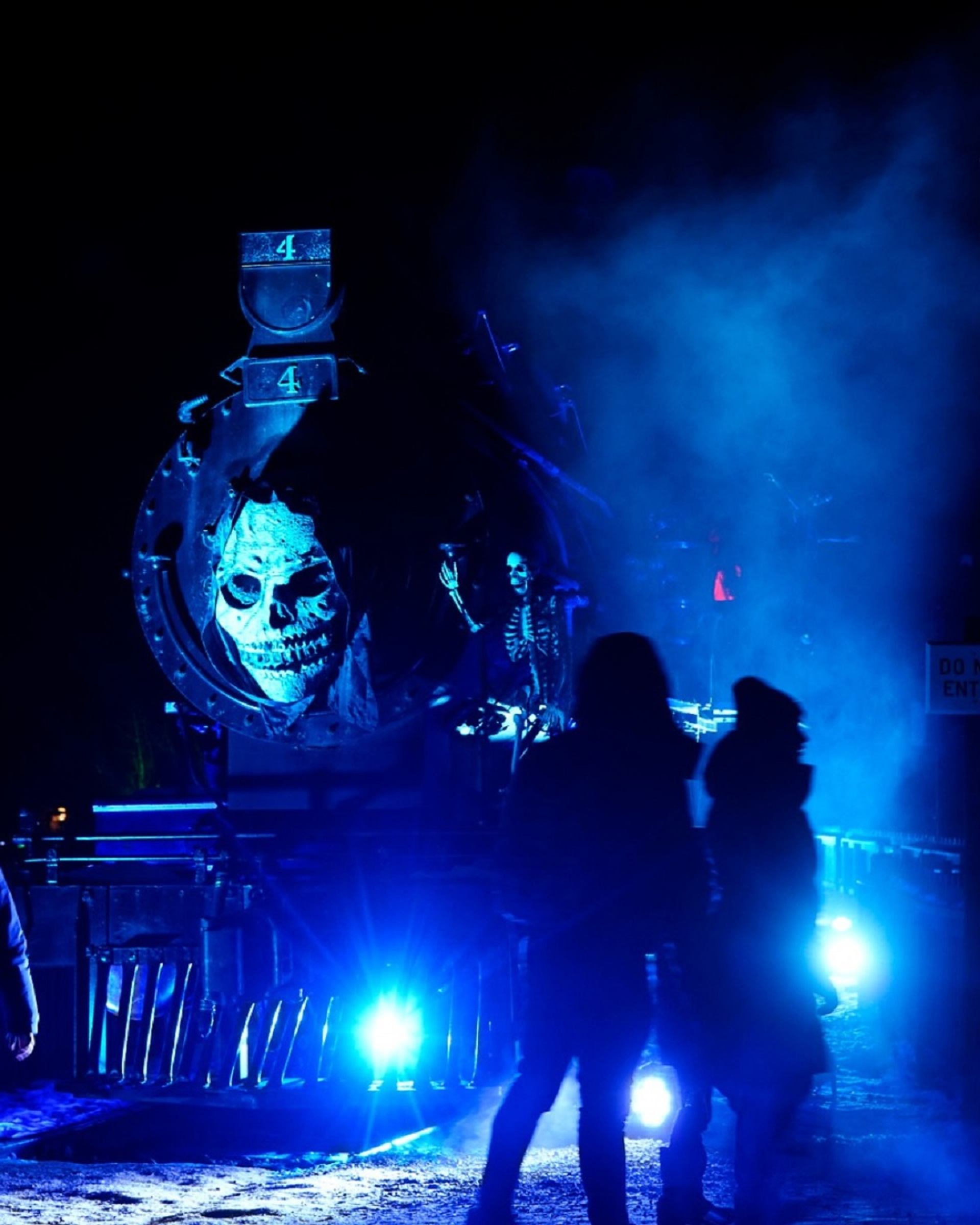 Foggy blue-lit scene with spooky train face and silhouettes at Ghouls' Night Out.
