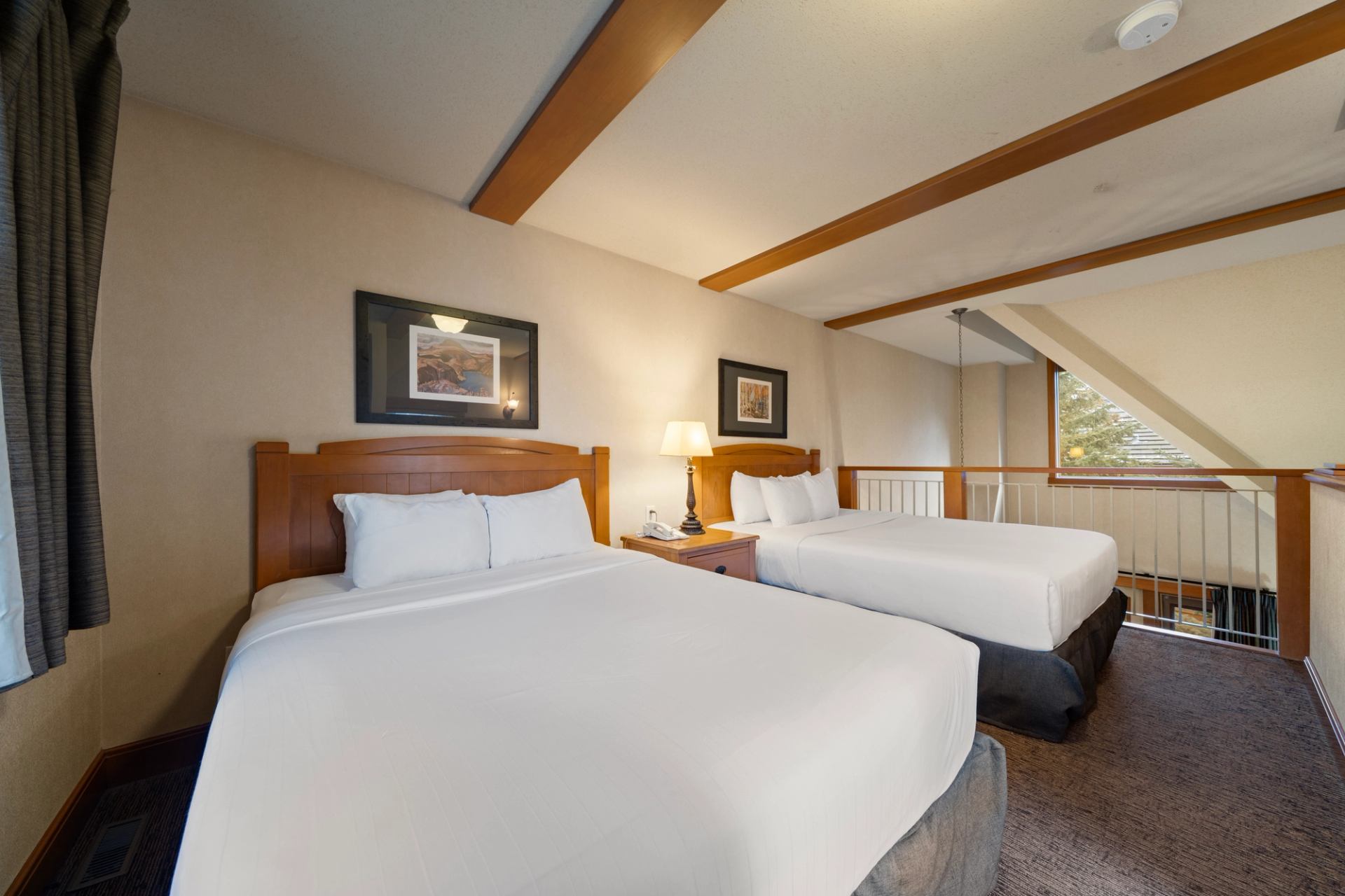 Two beds side by side in a loft that overlooks the living room below.