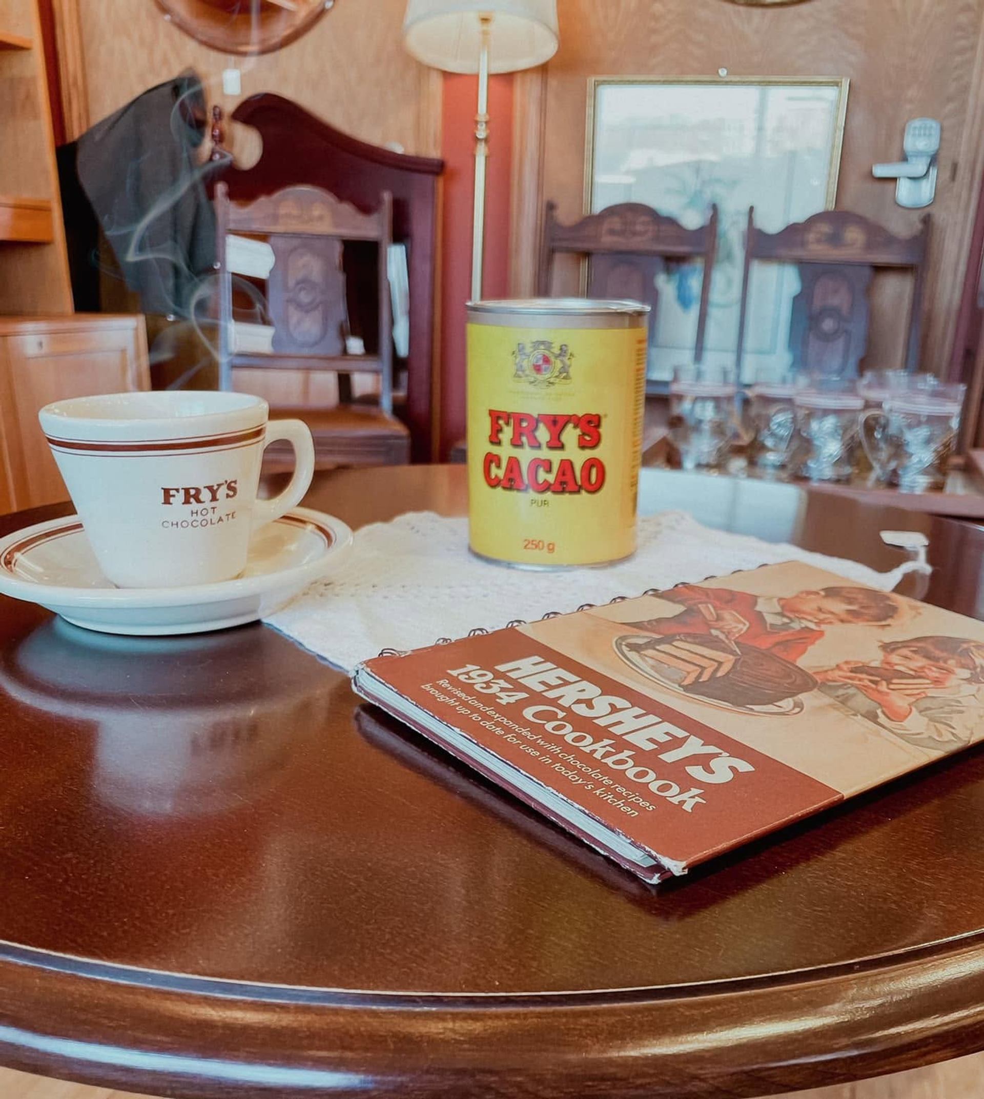 Round table with Fry’s hot chocolate cup, Fry’s cacao tin and Hershey’s cookbook.