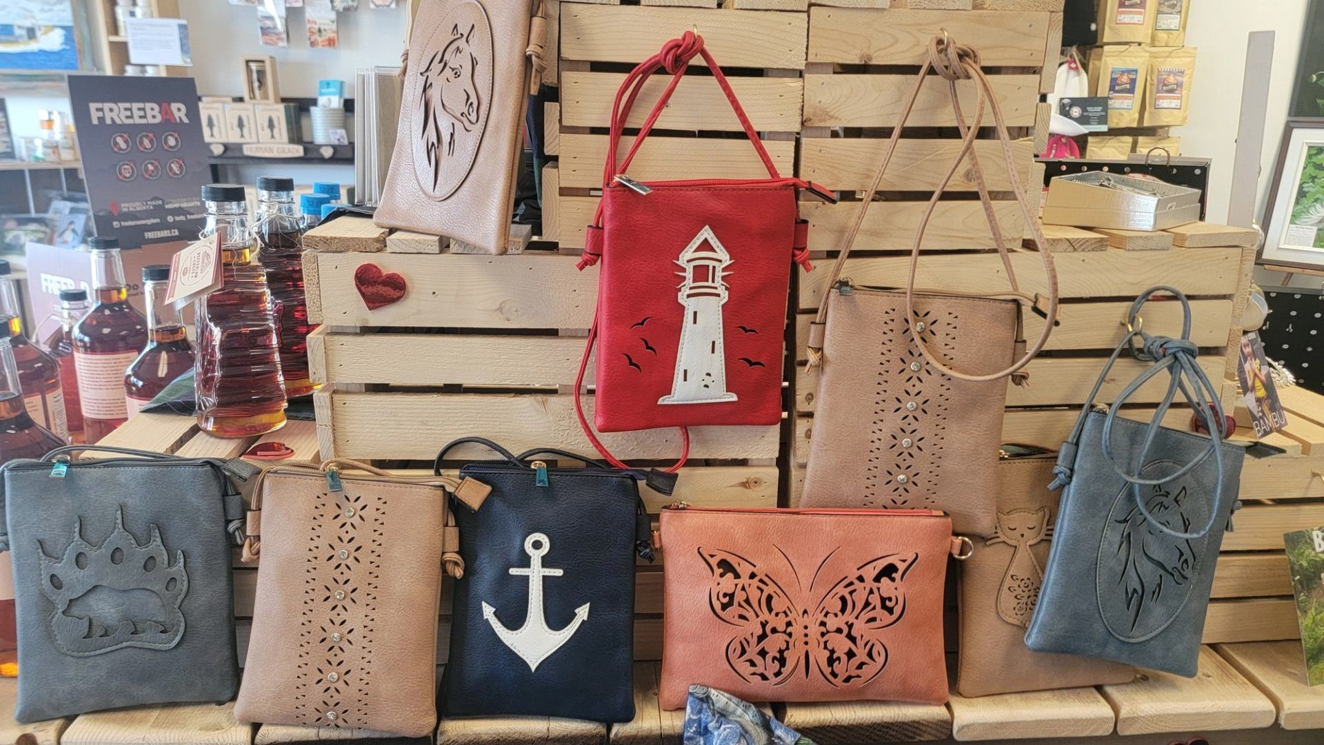 Eight leather bags with designs like horse, anchor, and butterfly on wooden crates in the store.