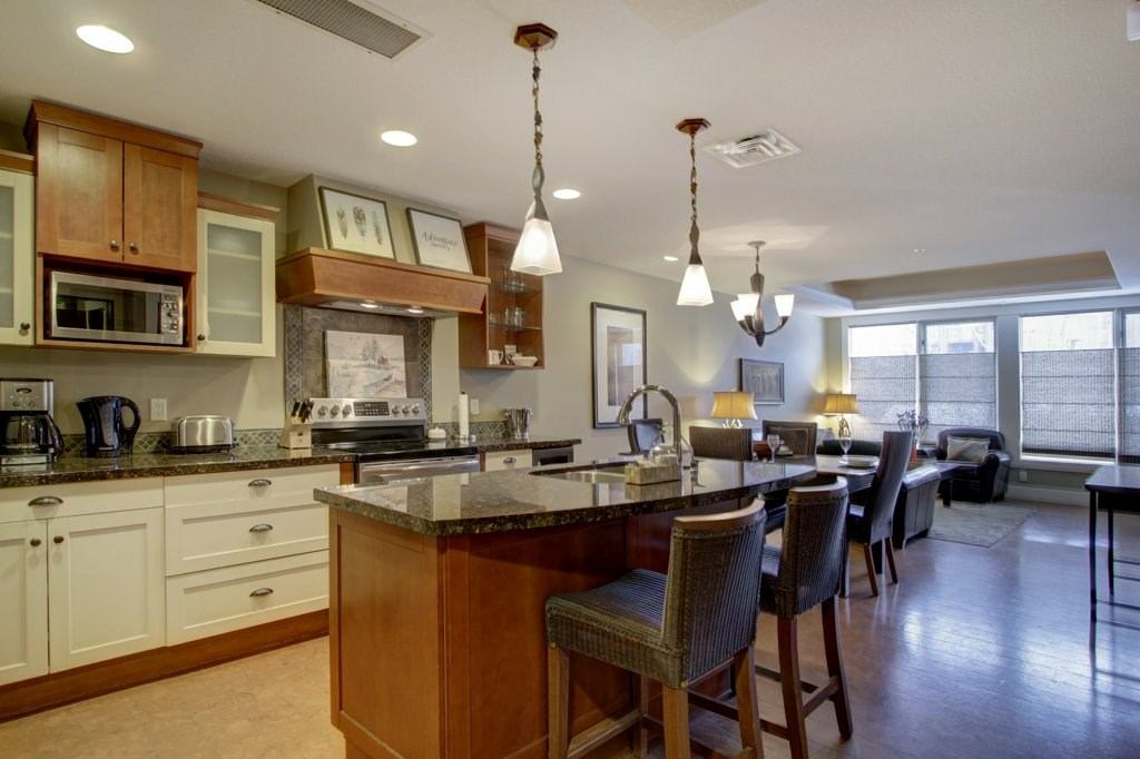 Modern kitchen with granite island, pendant lights, and open living area.