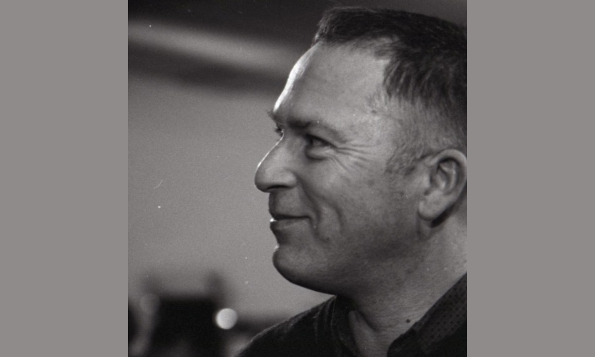 Black and white profile of a smiling man.