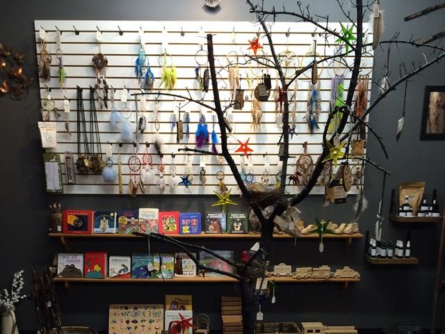 A tree adorned with dreamcatchers and smudging supplies, alongside a shelf filled with calming items.