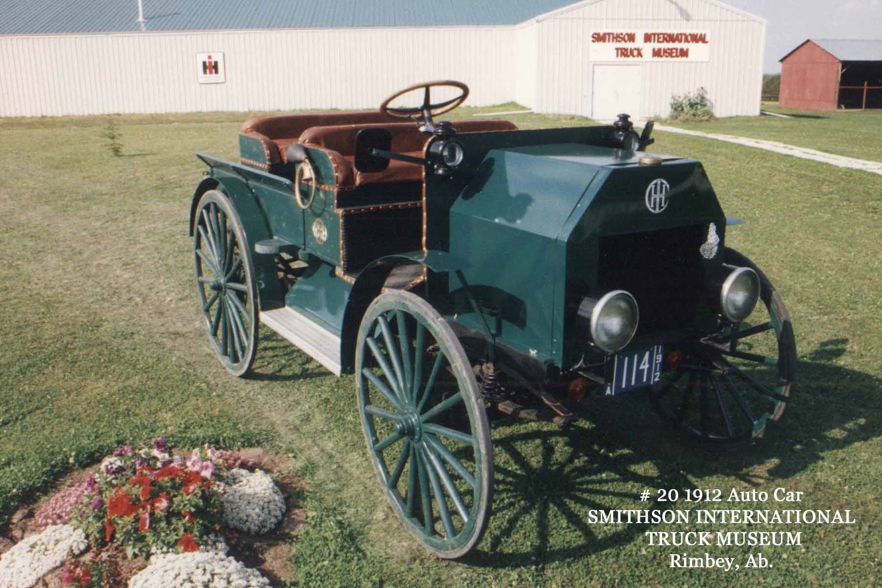 Green vintage 1912 car in front of museum building