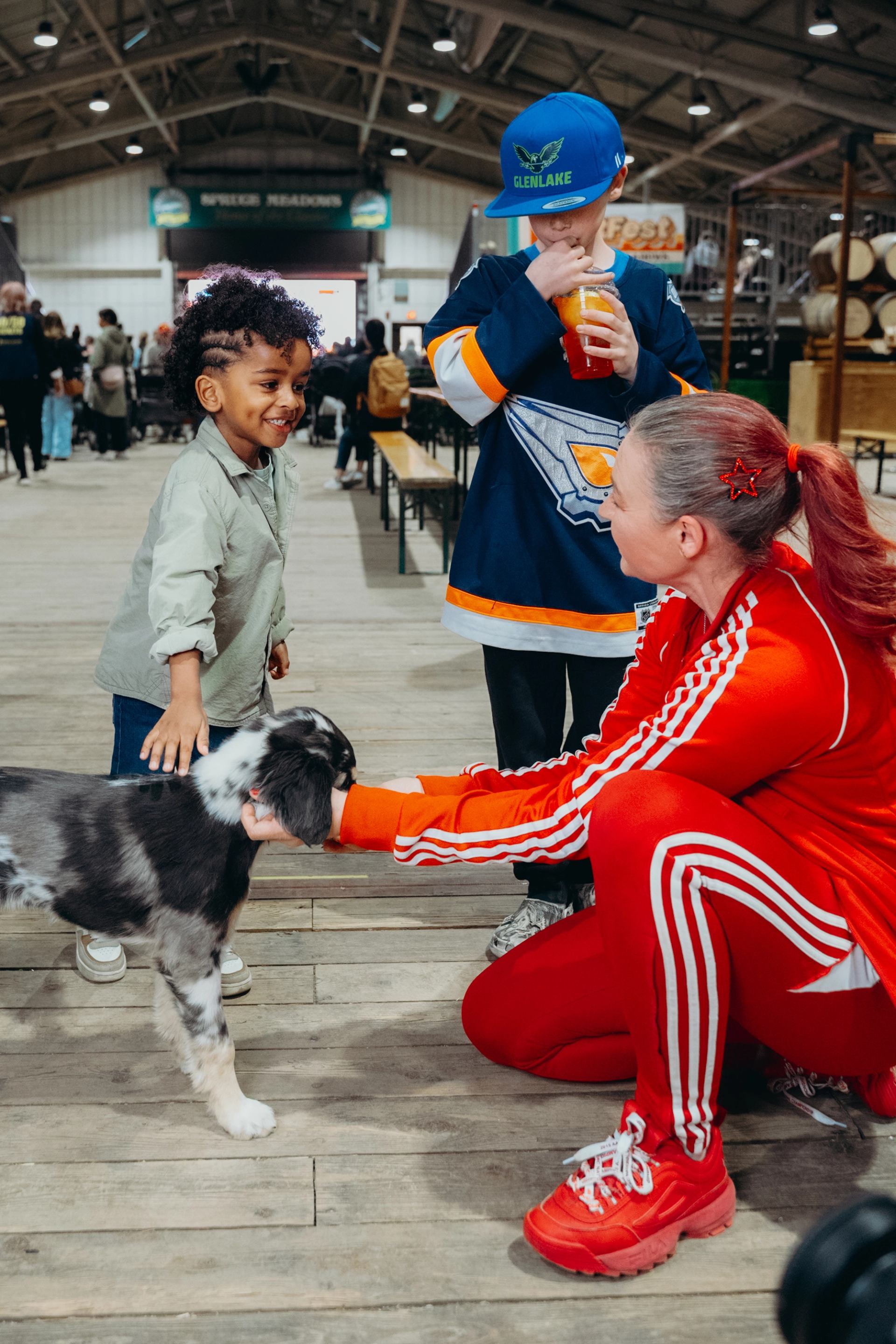 Children interact with a friendly dog while an adult kneels beside them.