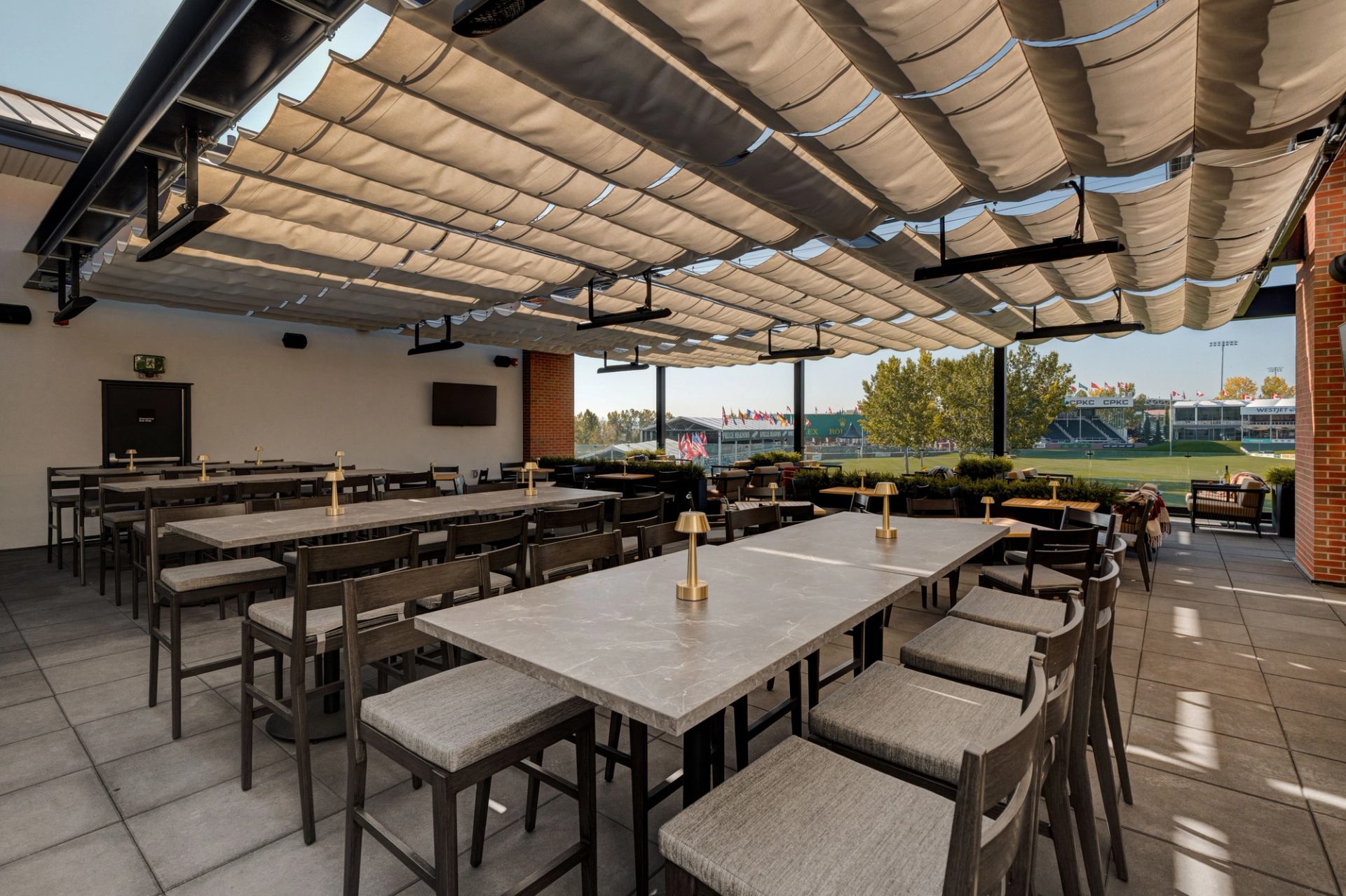 Covered terrace at Foxtrot at Spruce Meadows with long tables, shaded ceiling, and outdoor seating.