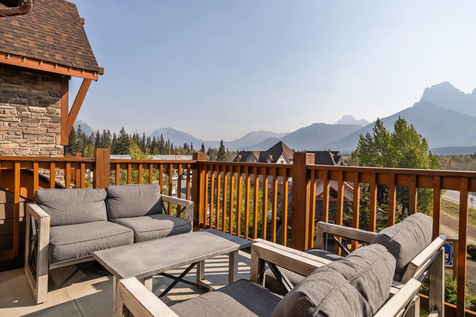 Balcony seating overlooks trees, rooftops and distant mountain peaks.