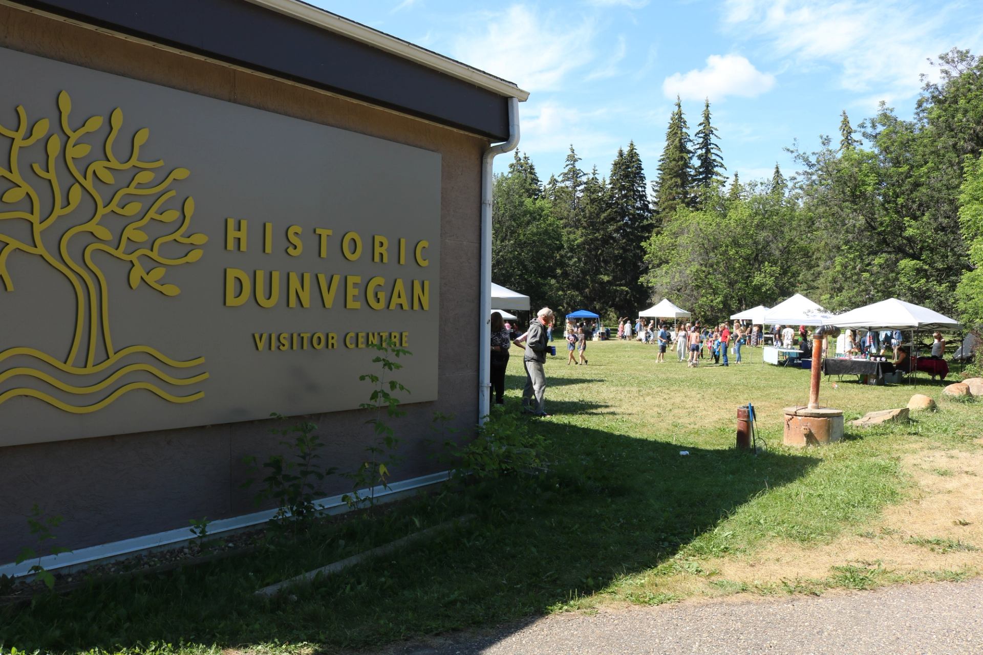 Historic Dunvegan Visitor Centre with tents and visitors at an outdoor market.