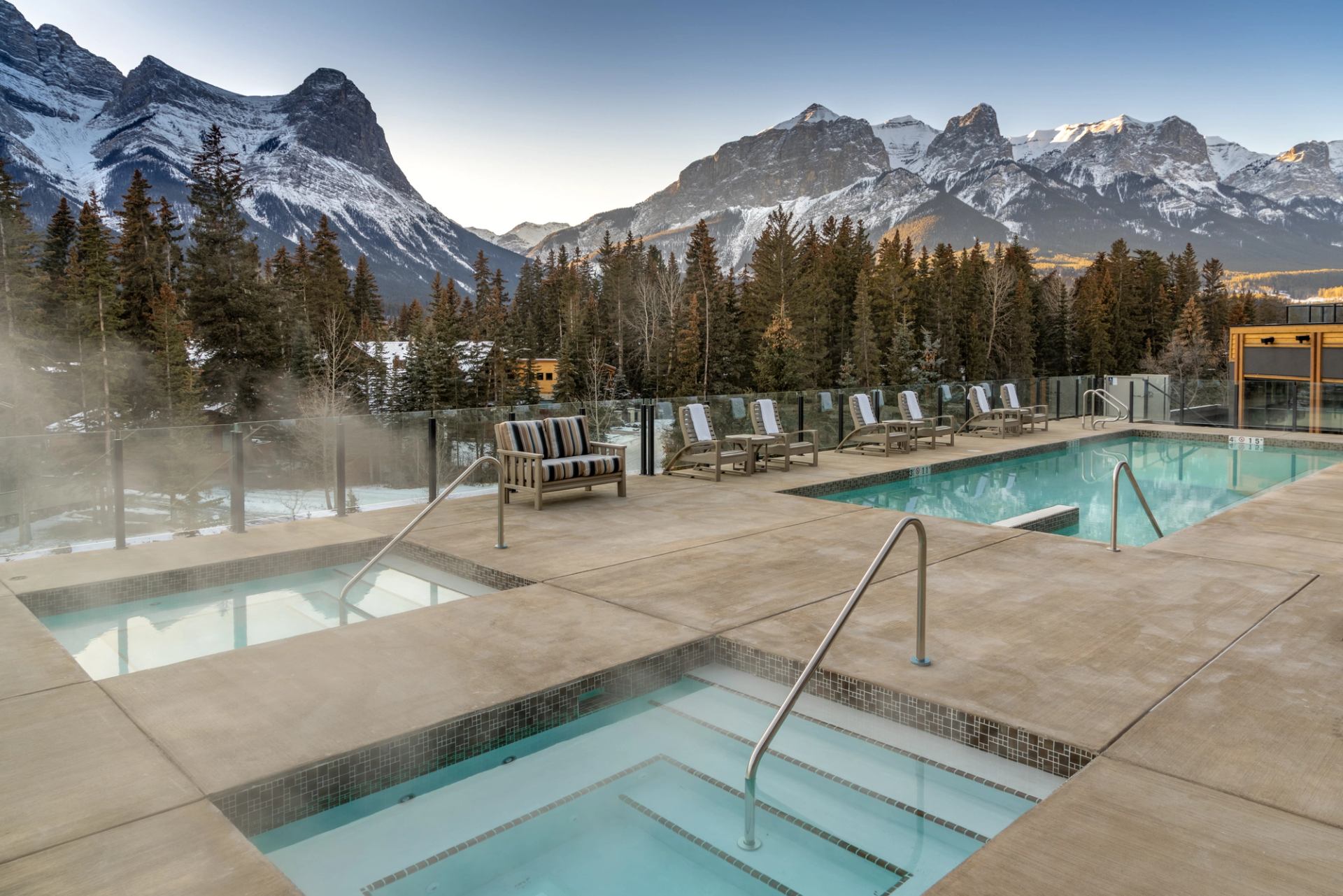 Outdoor pools and hot tubs overlooking snow-covered Rocky Mountain peaks.