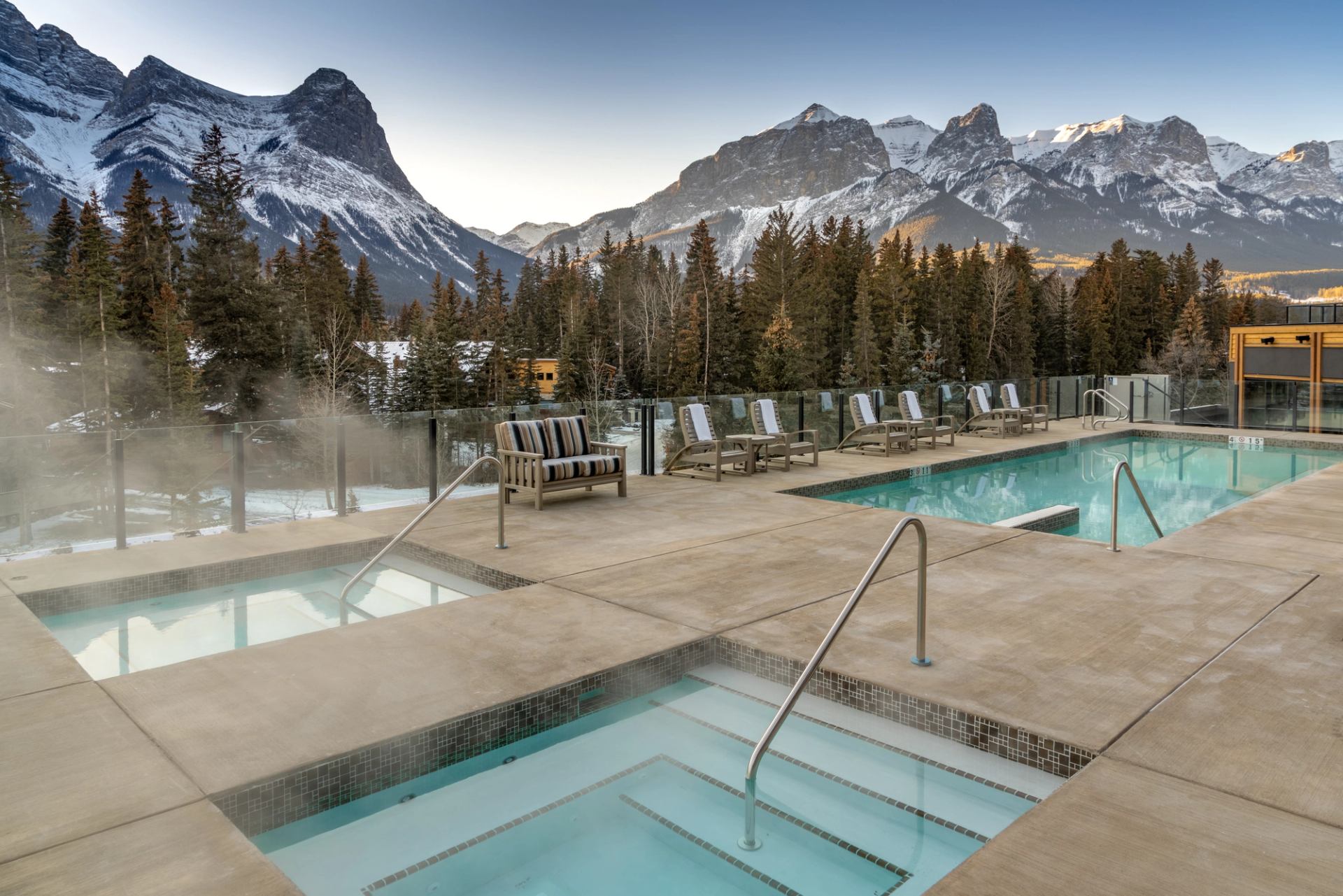 Outdoor pools and hot tubs overlooking snow-covered Rocky Mountain peaks.