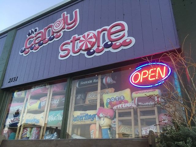 Candy and ice cream shop storefront with “Crazy Cady” sign, “OPEN” neon, and window displays.